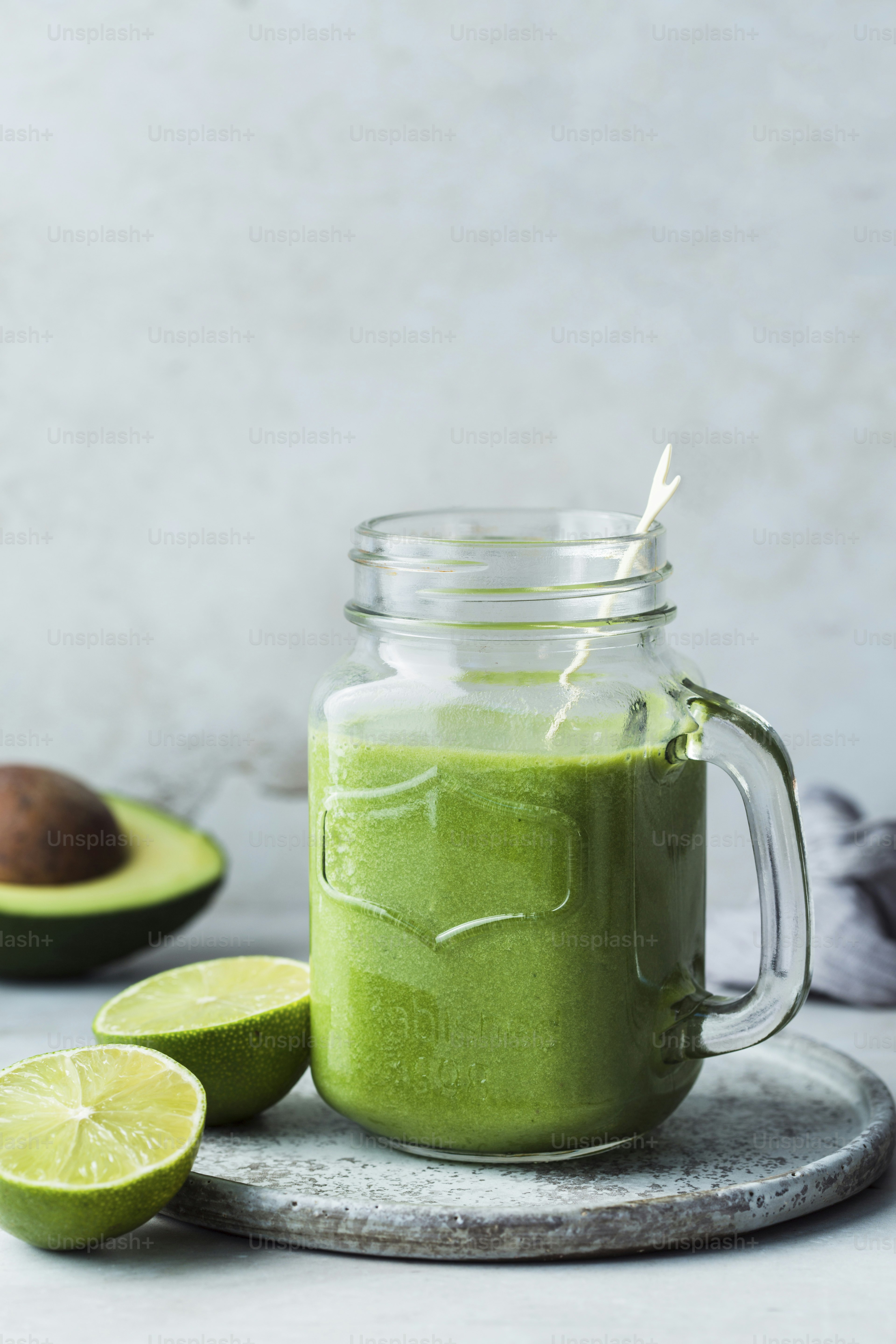 A green smoothie in a mason jar with a straw