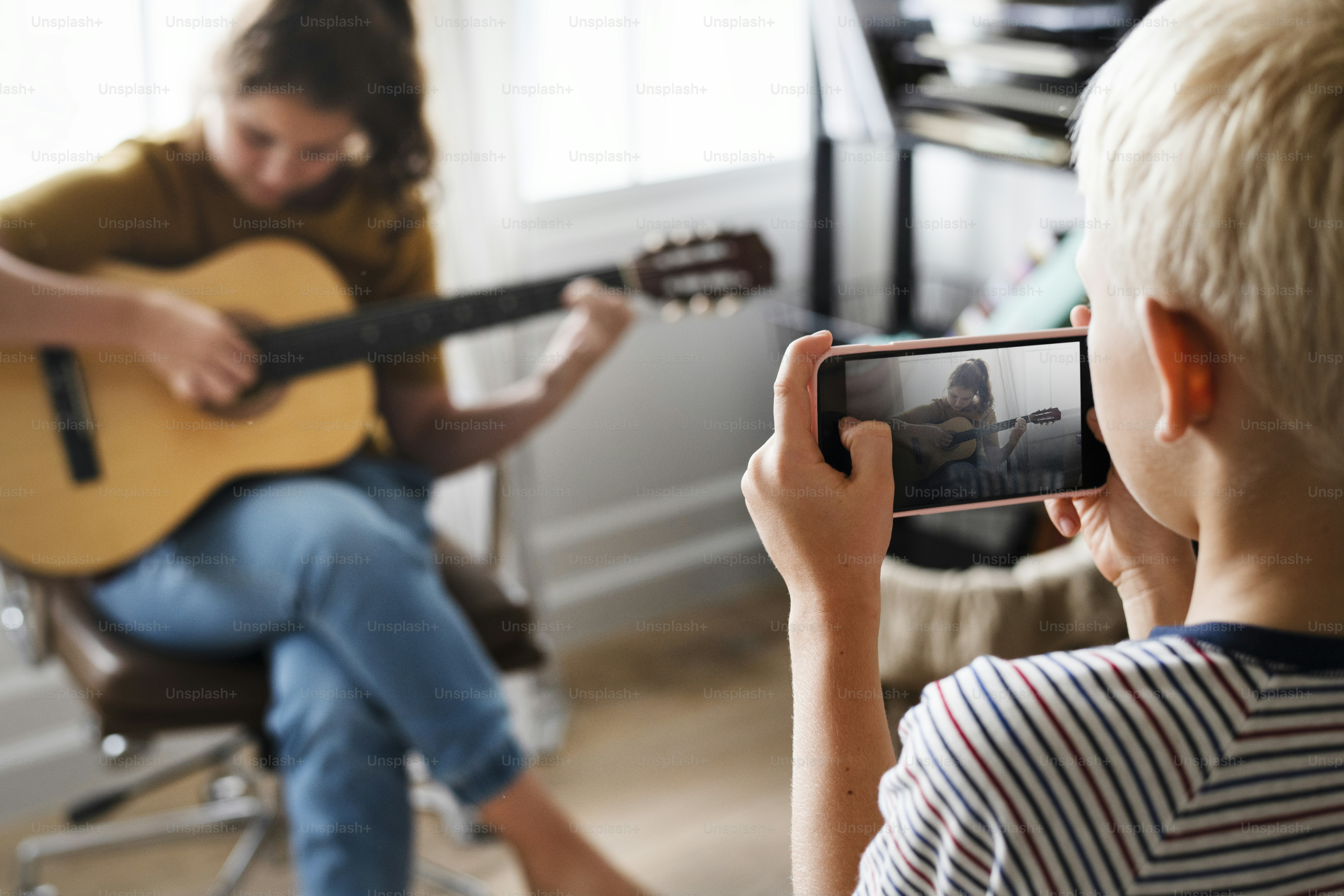 Brother recording his sister playing the guitar