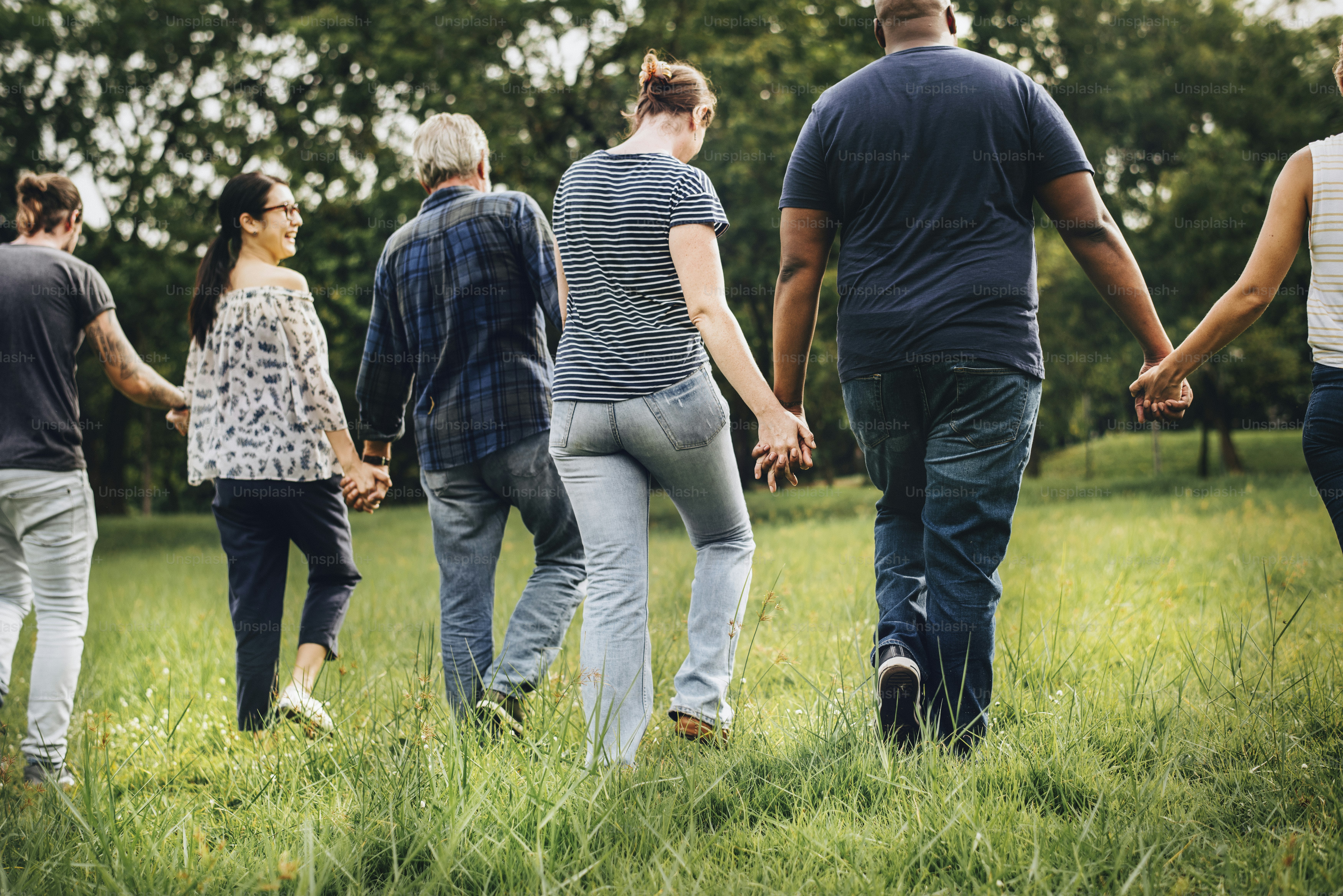 Diverse people holding hands and running in the park