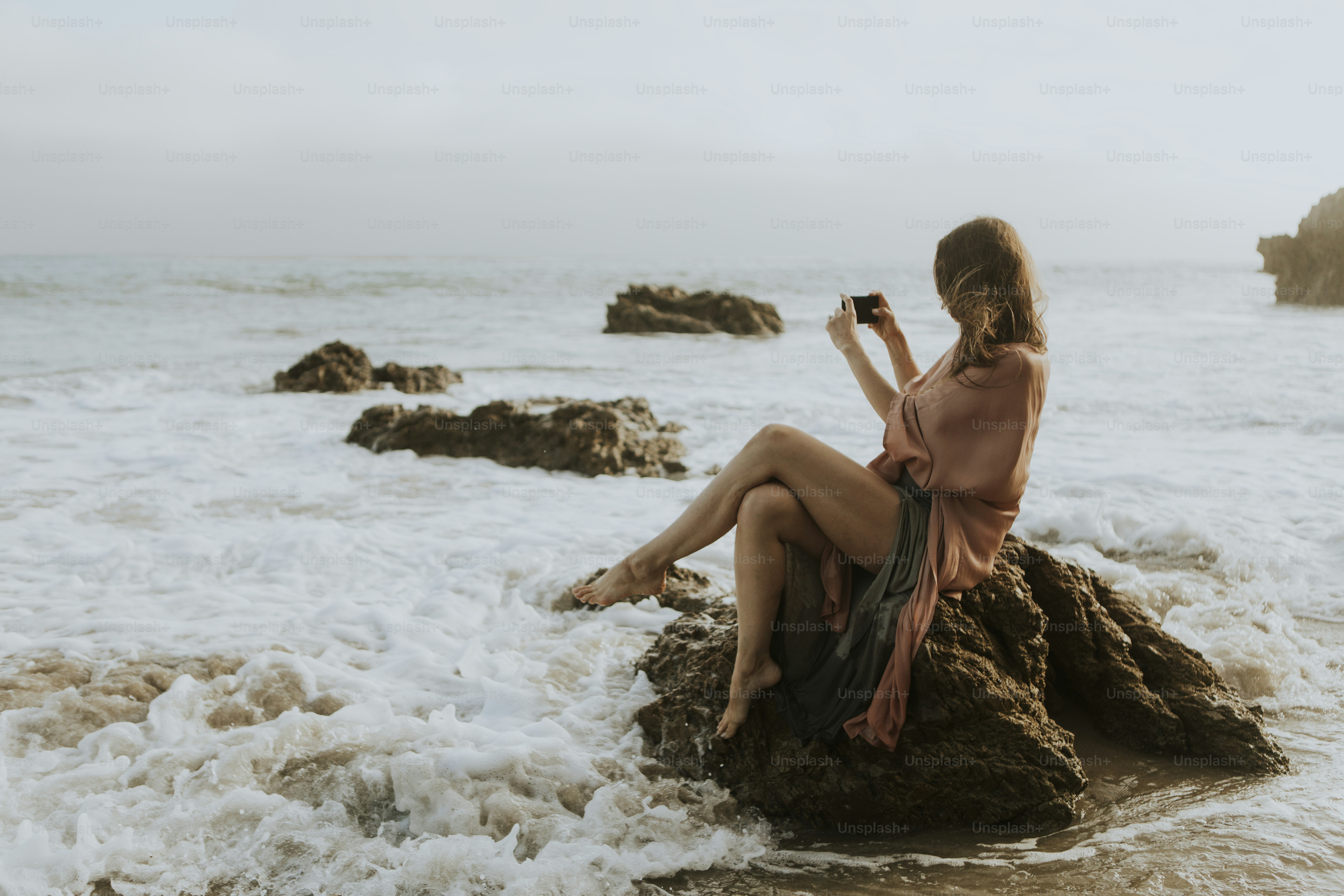 Woman taking photos with her phone on the beach