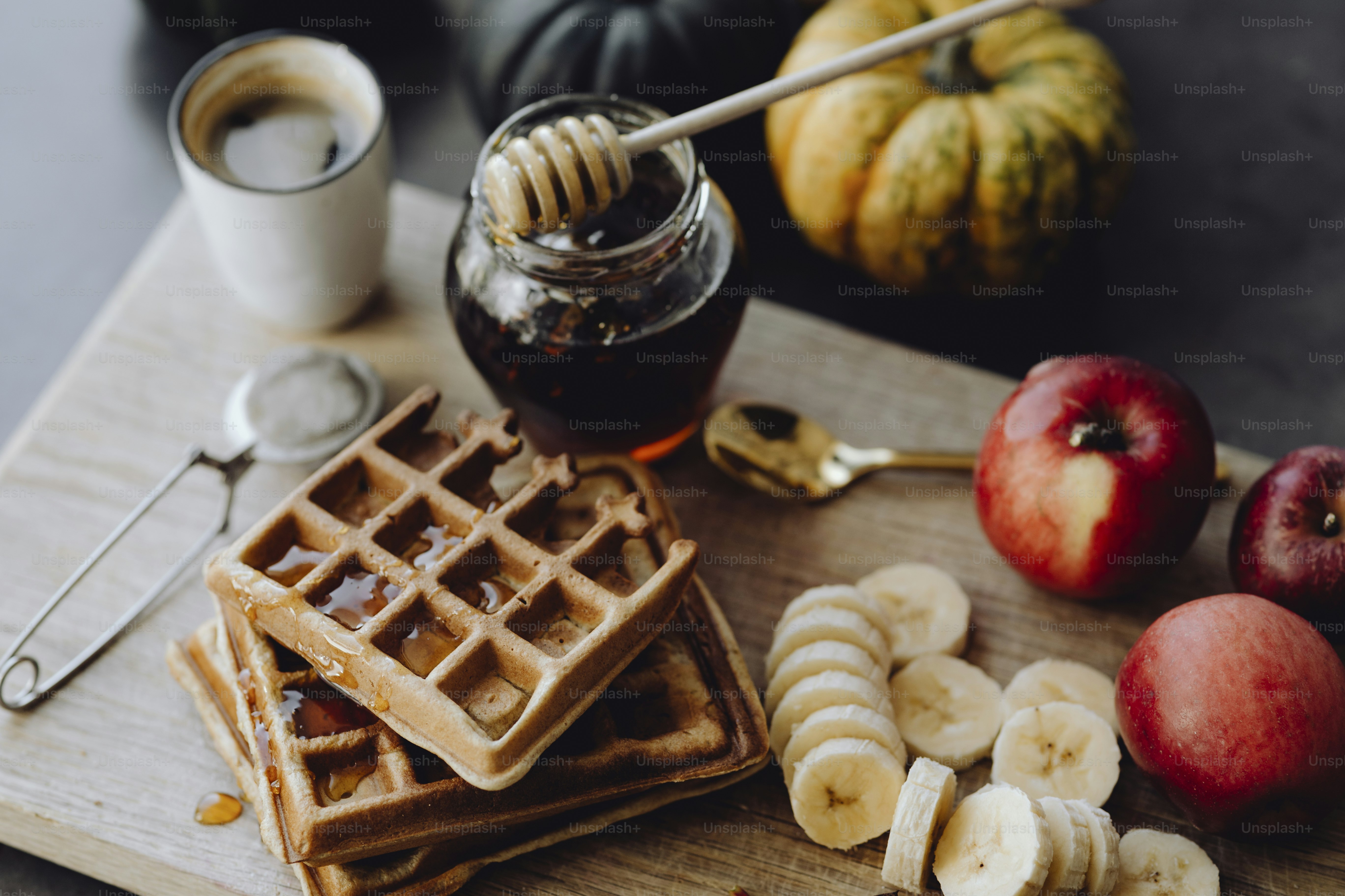 Waffle and slices of banana on a wooden tray next to a honey jar