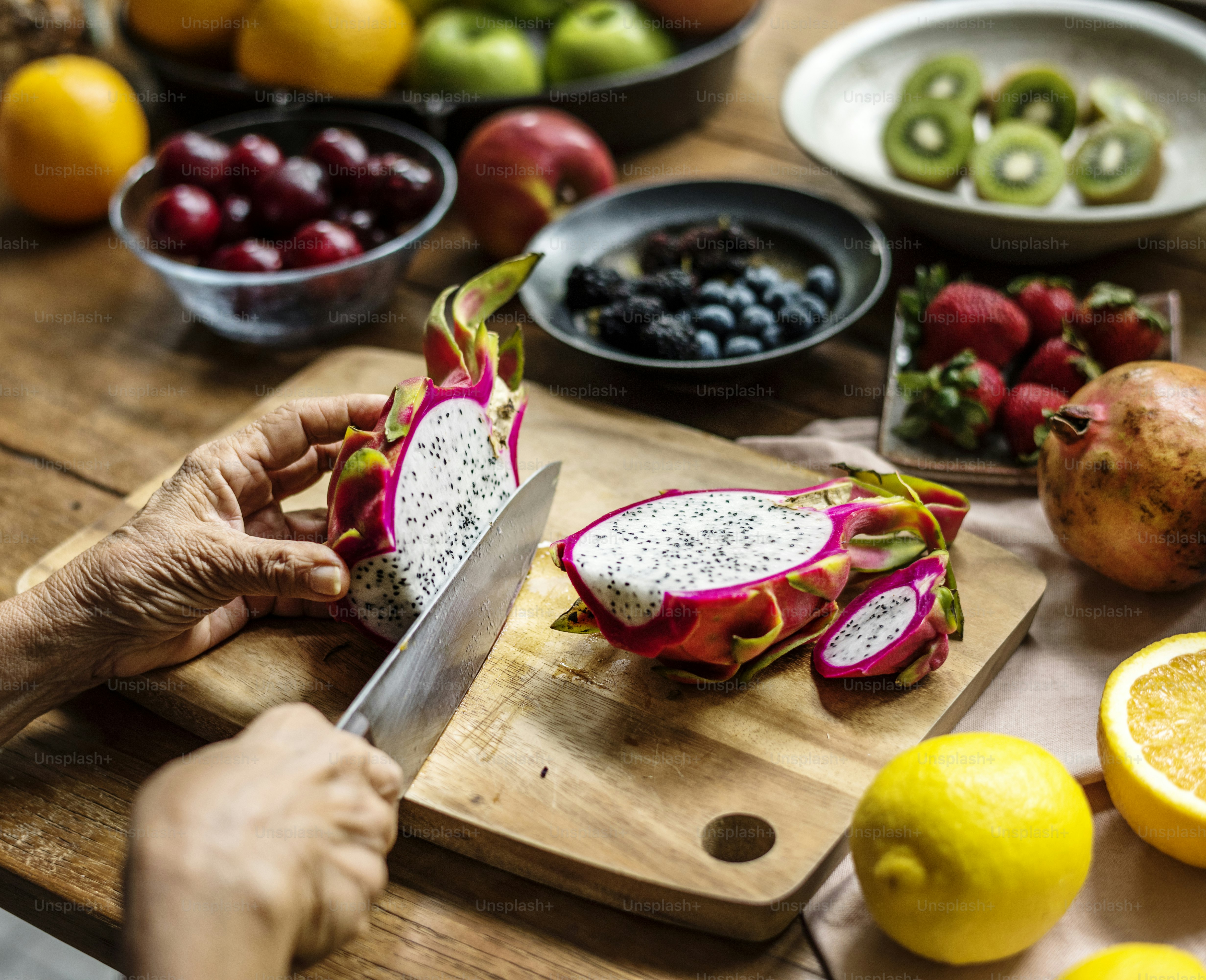 Closeup of hand with knife cutting dragon fruit