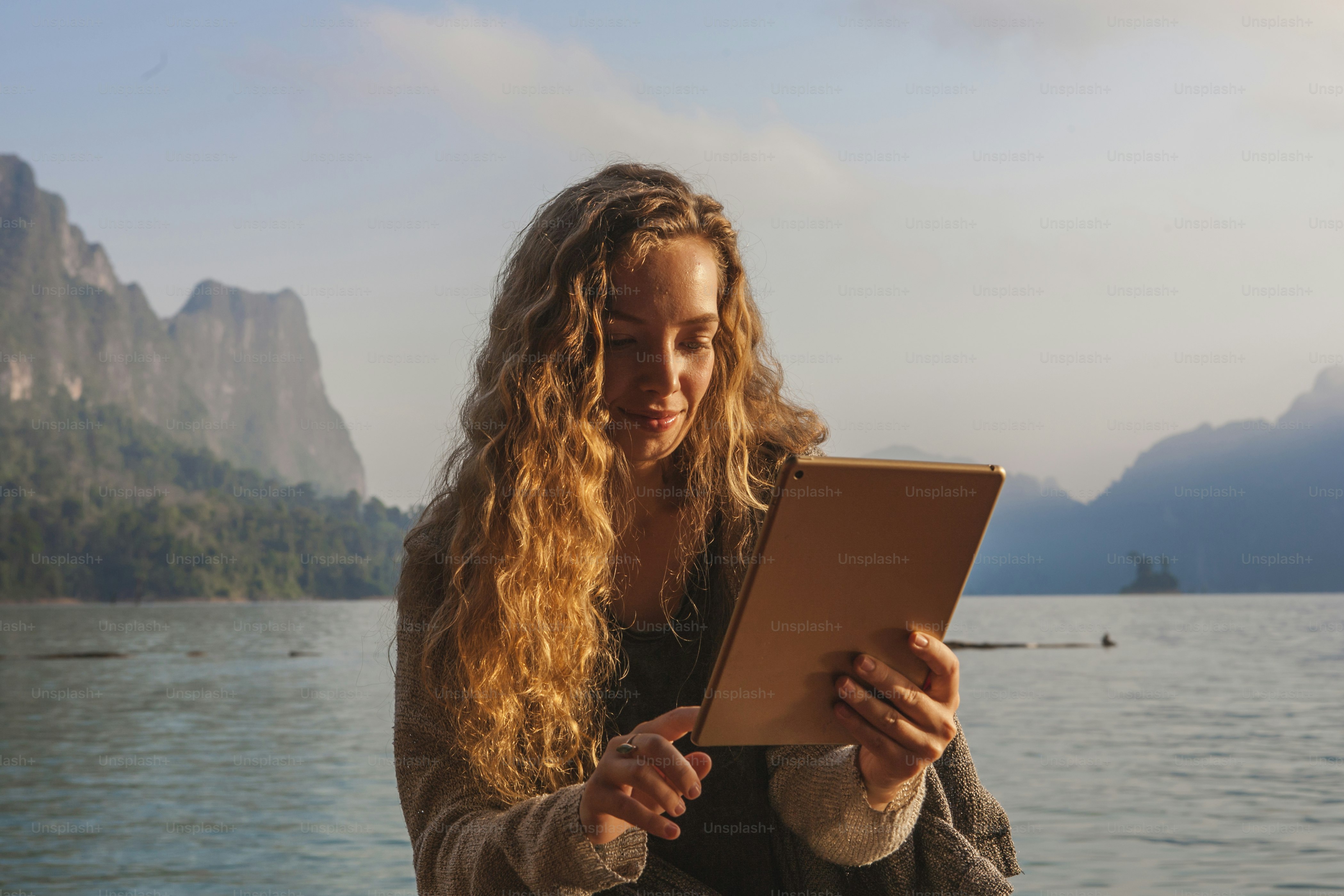 Woman using her tablet by a lake