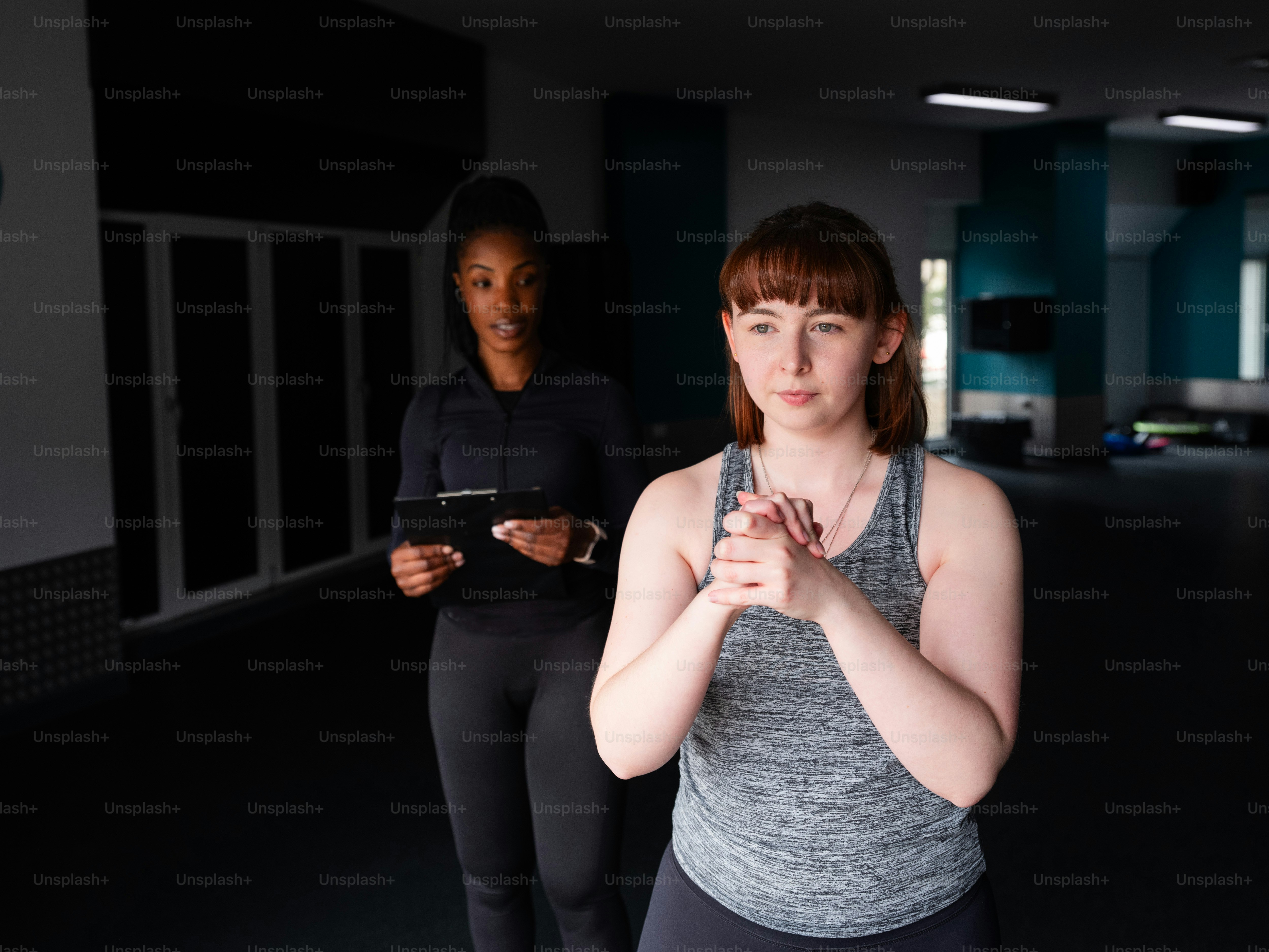 Deux femmes debout dans une pièce sombre en train de regarder leur téléphone