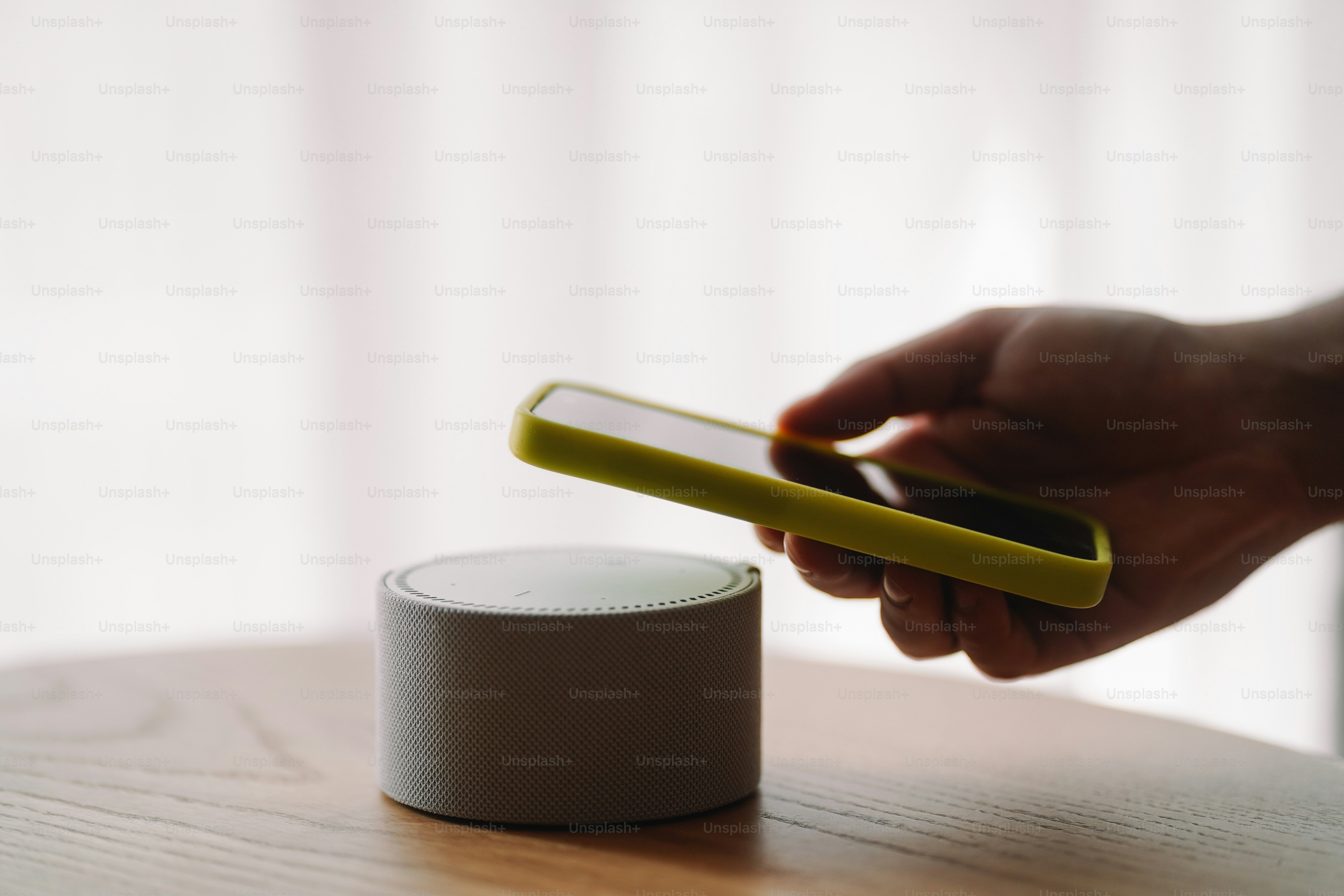 A person holding a cell phone next to a smart device