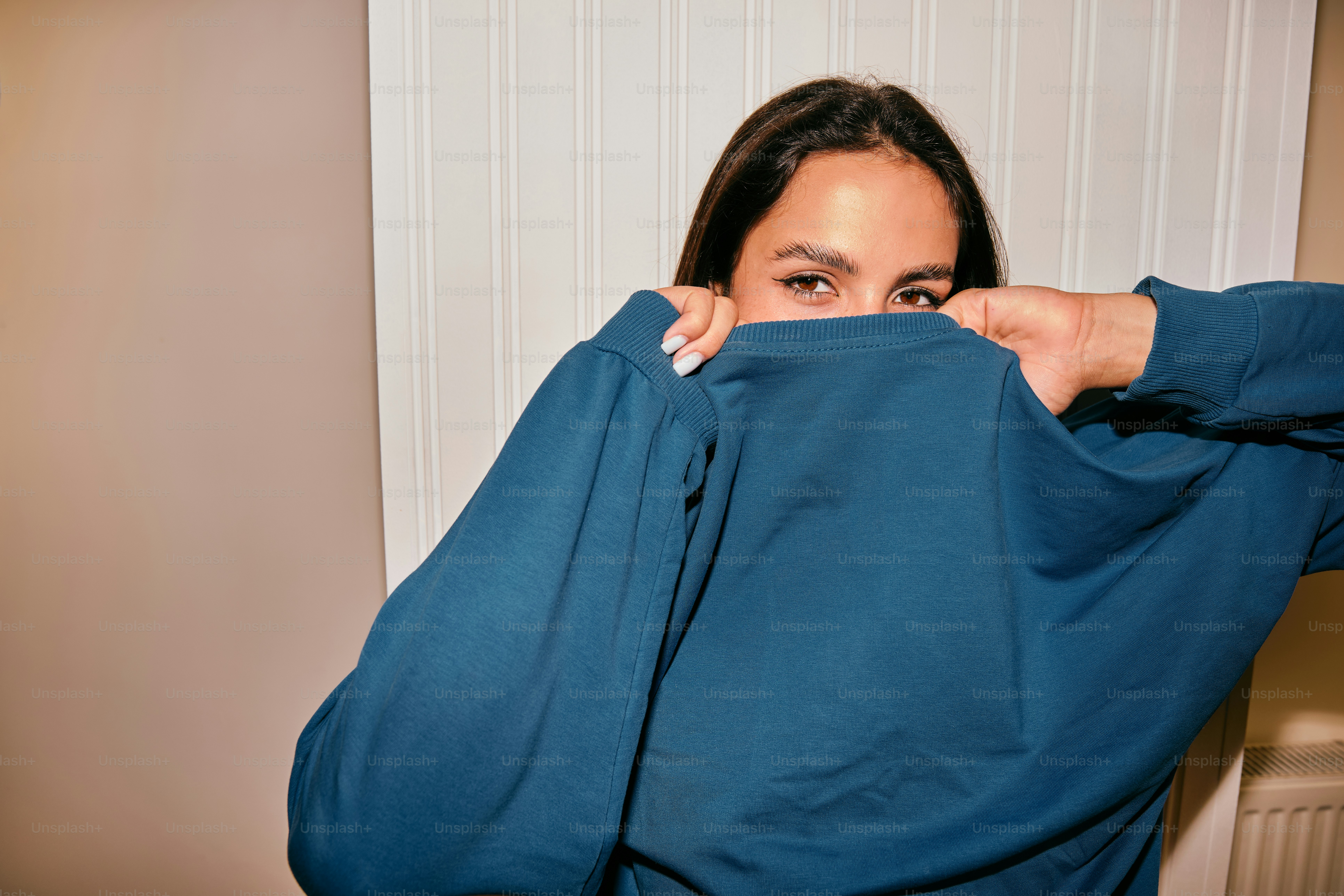 A woman covering her face with a blue shirt