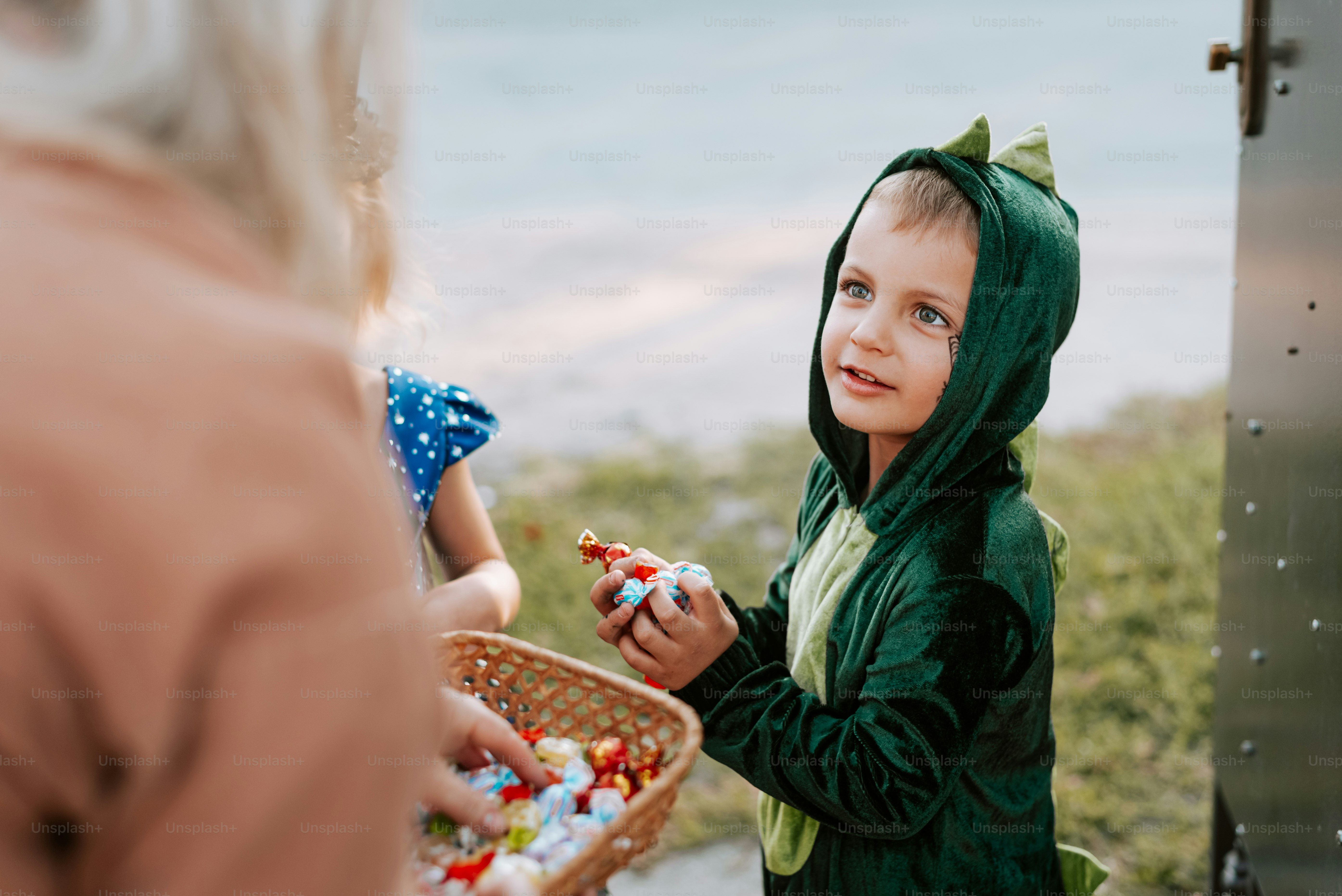 A little girl in a green hoodie holding a basket of candy