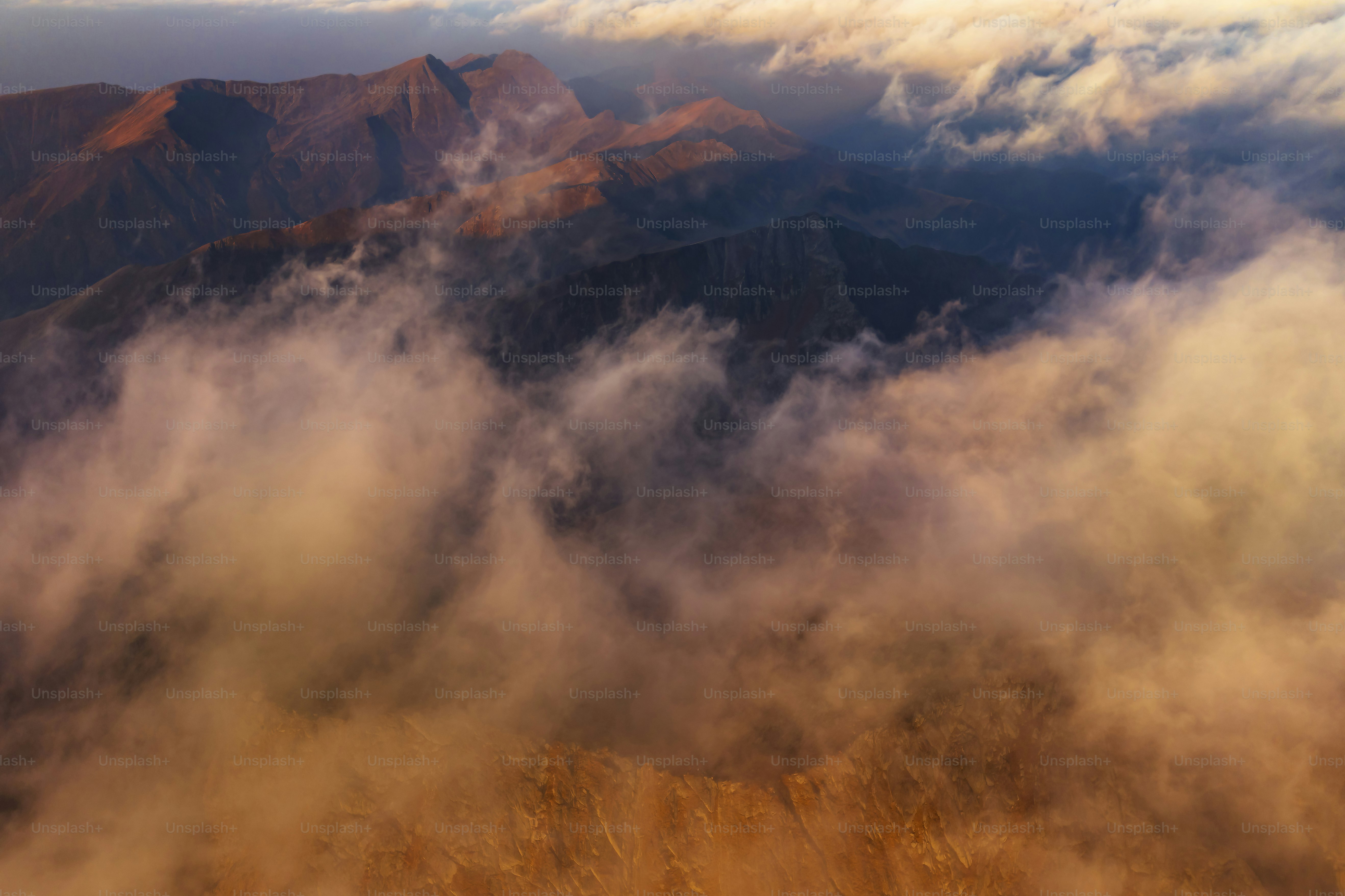 An aerial view of a mountain range covered in clouds