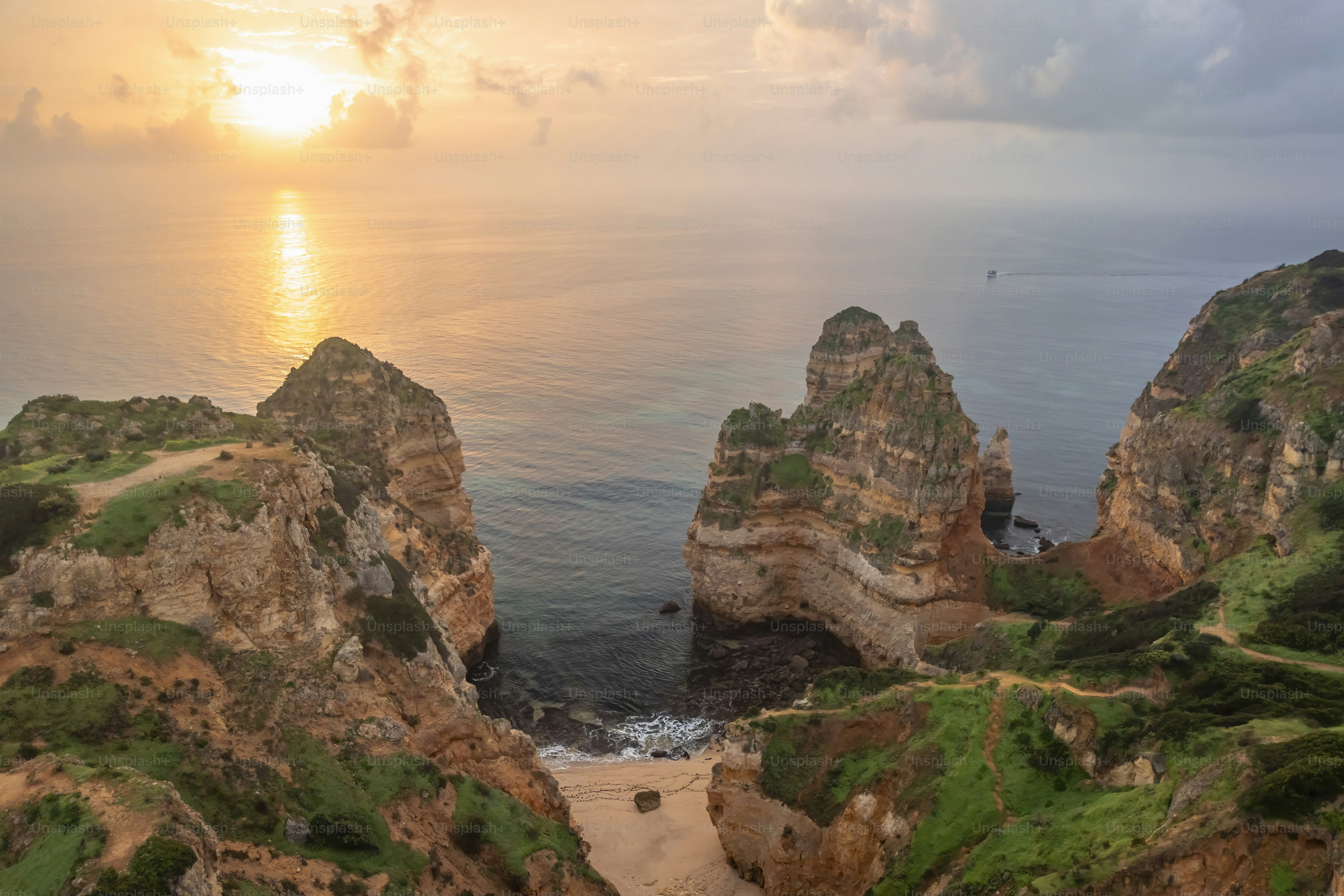 The sun is setting over the ocean and rocks