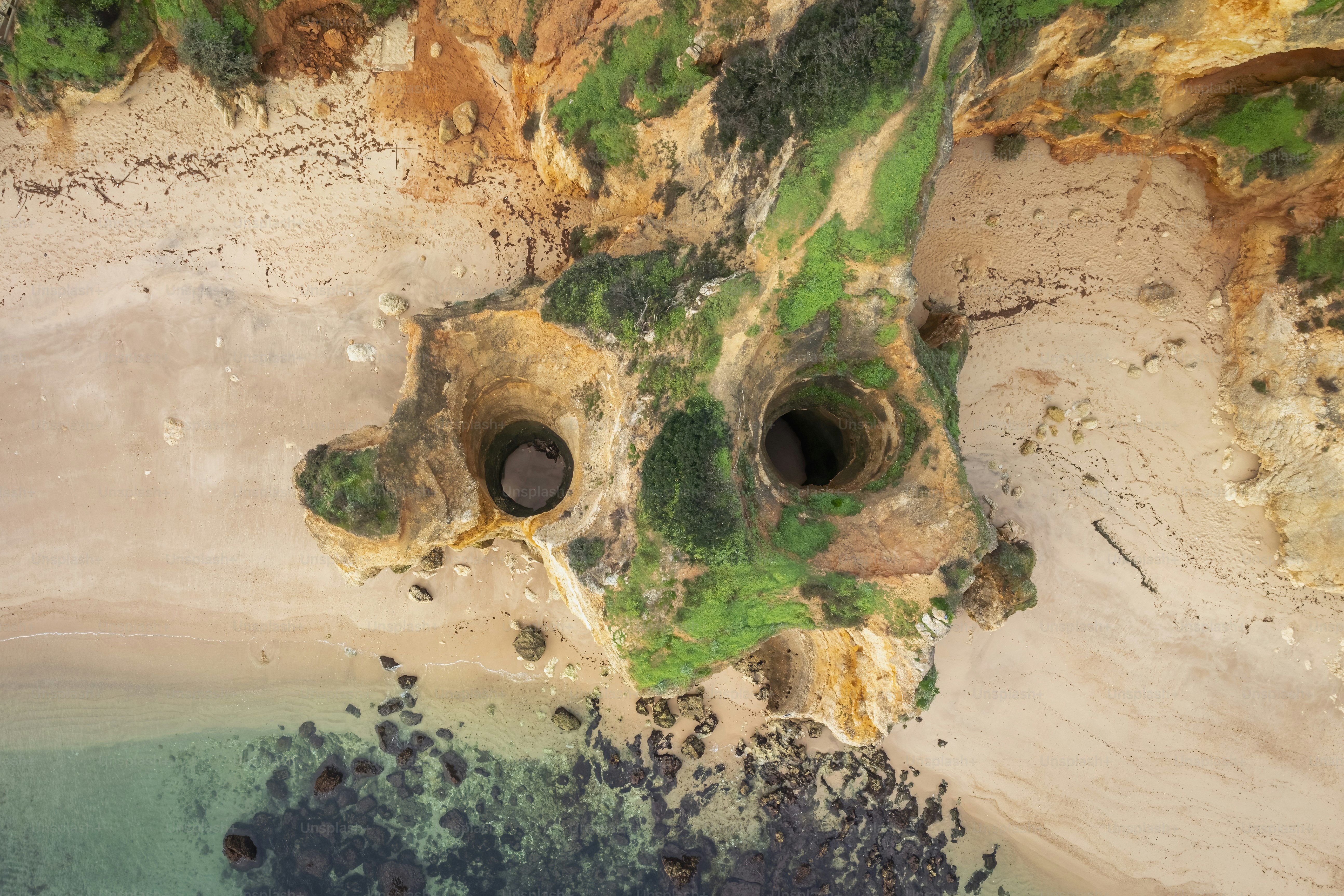 An aerial view of a sandy beach with green trees