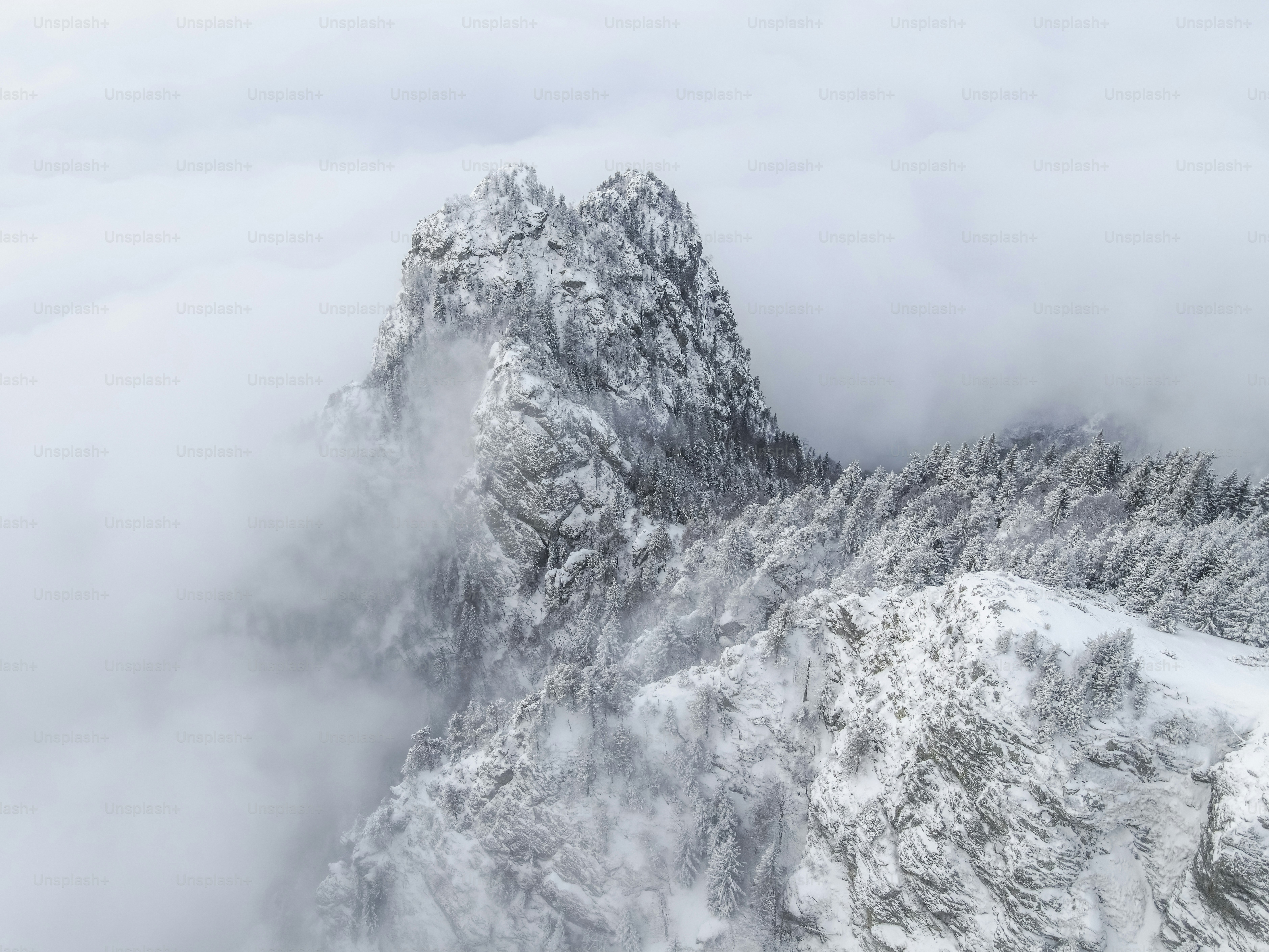 A mountain covered in snow and clouds under a cloudy sky