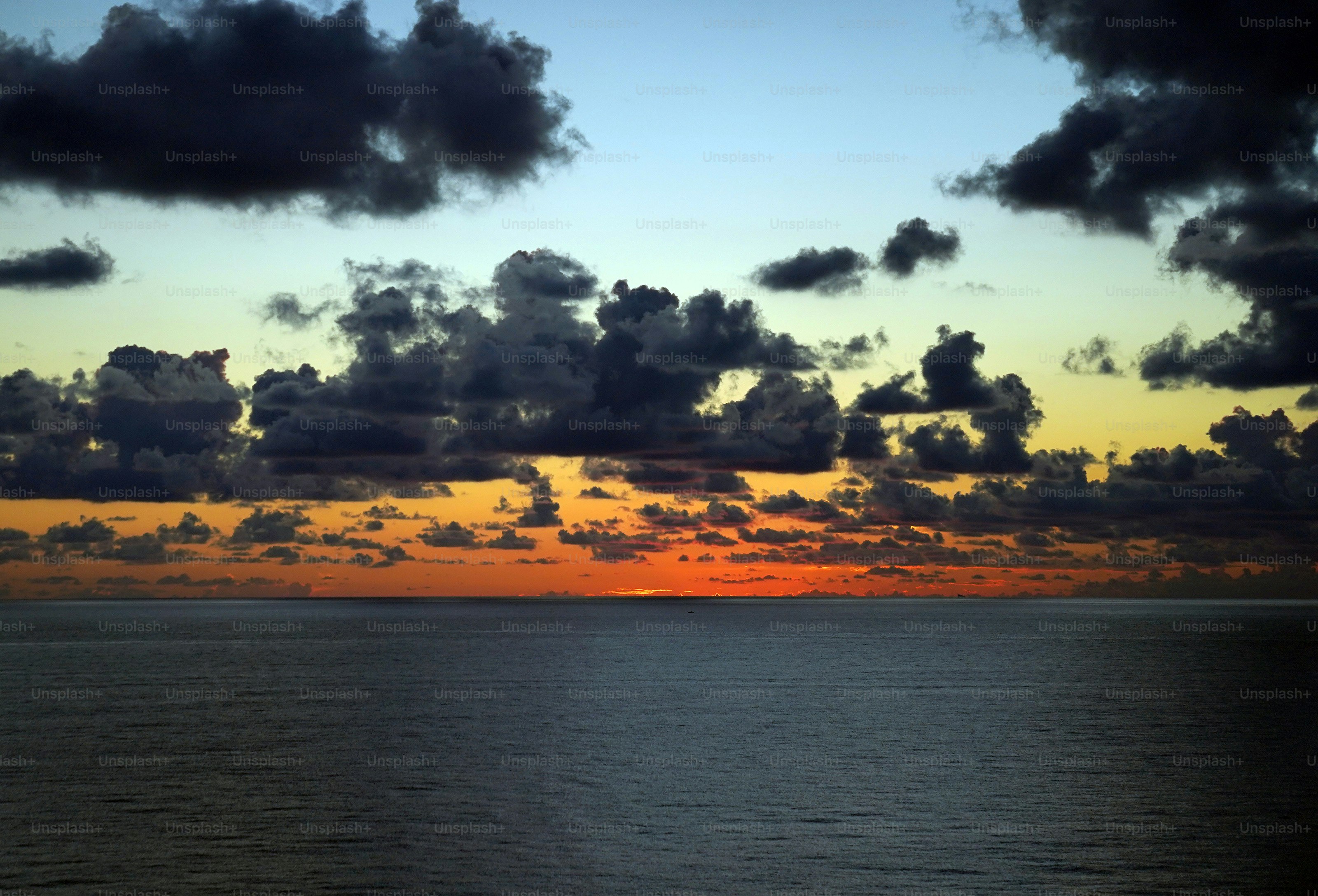 Die Sonne geht an einem bewölkten Tag über dem Meer unter