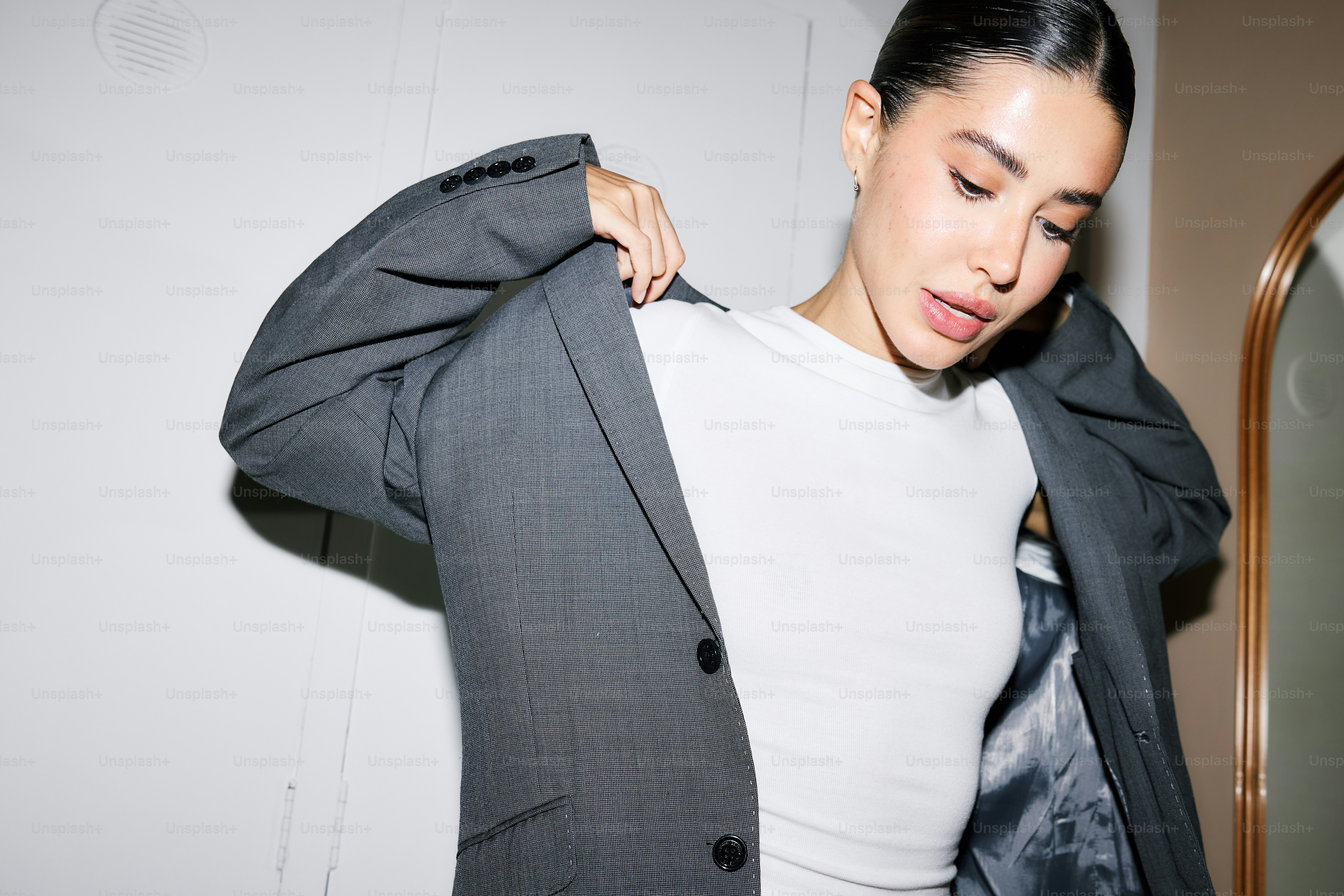A woman standing in front of a mirror holding onto a jacket