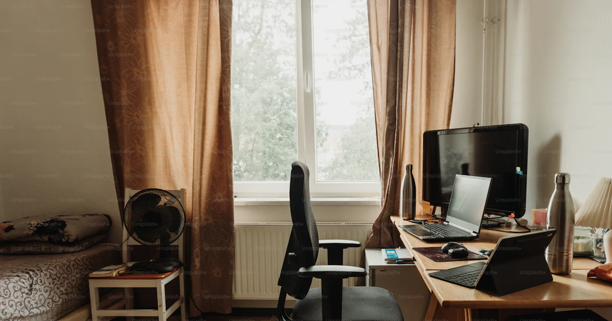 A bedroom with a bed, desk, and computer photo – Dorm room Image on ...