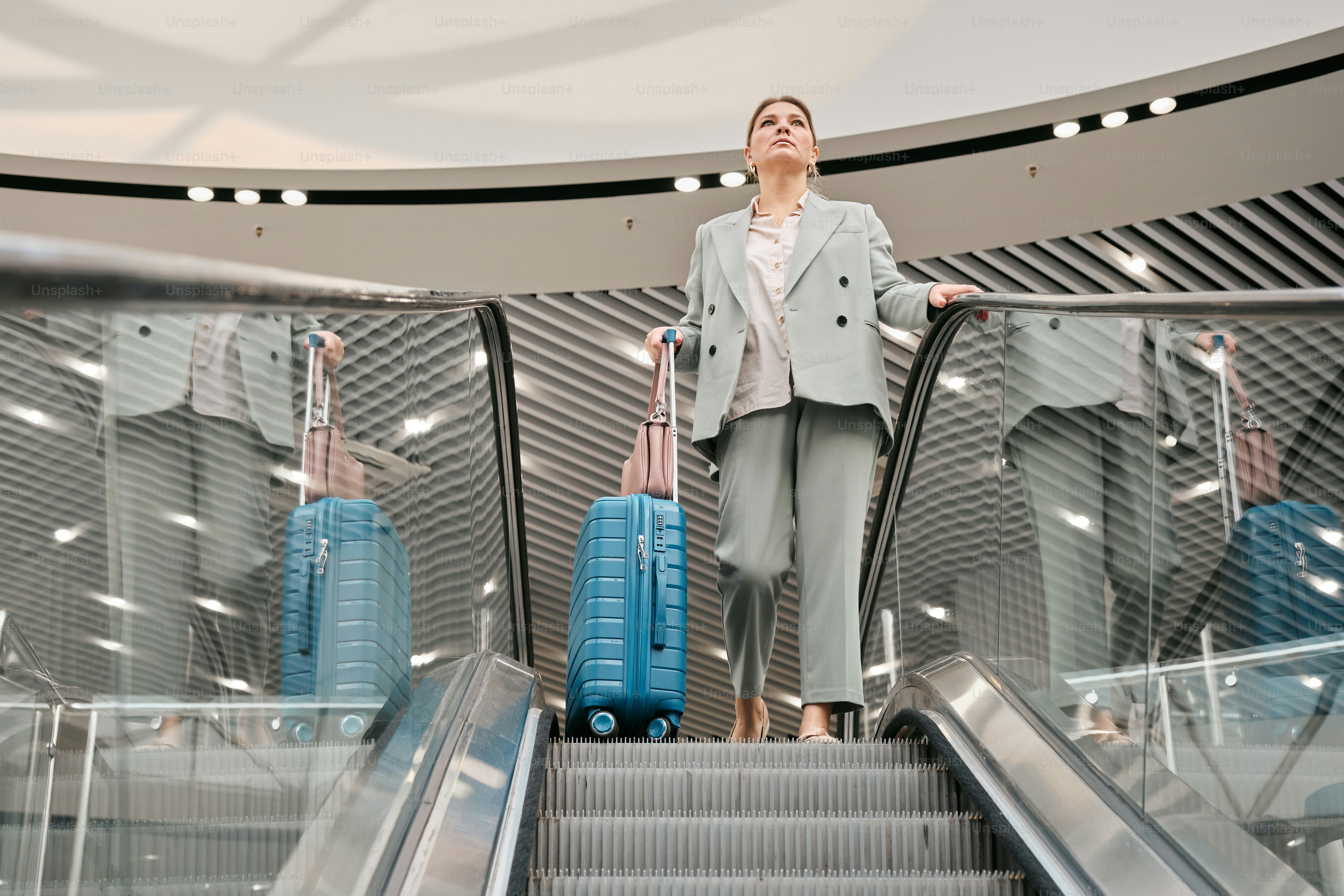 A woman standing on an escalator with her luggage