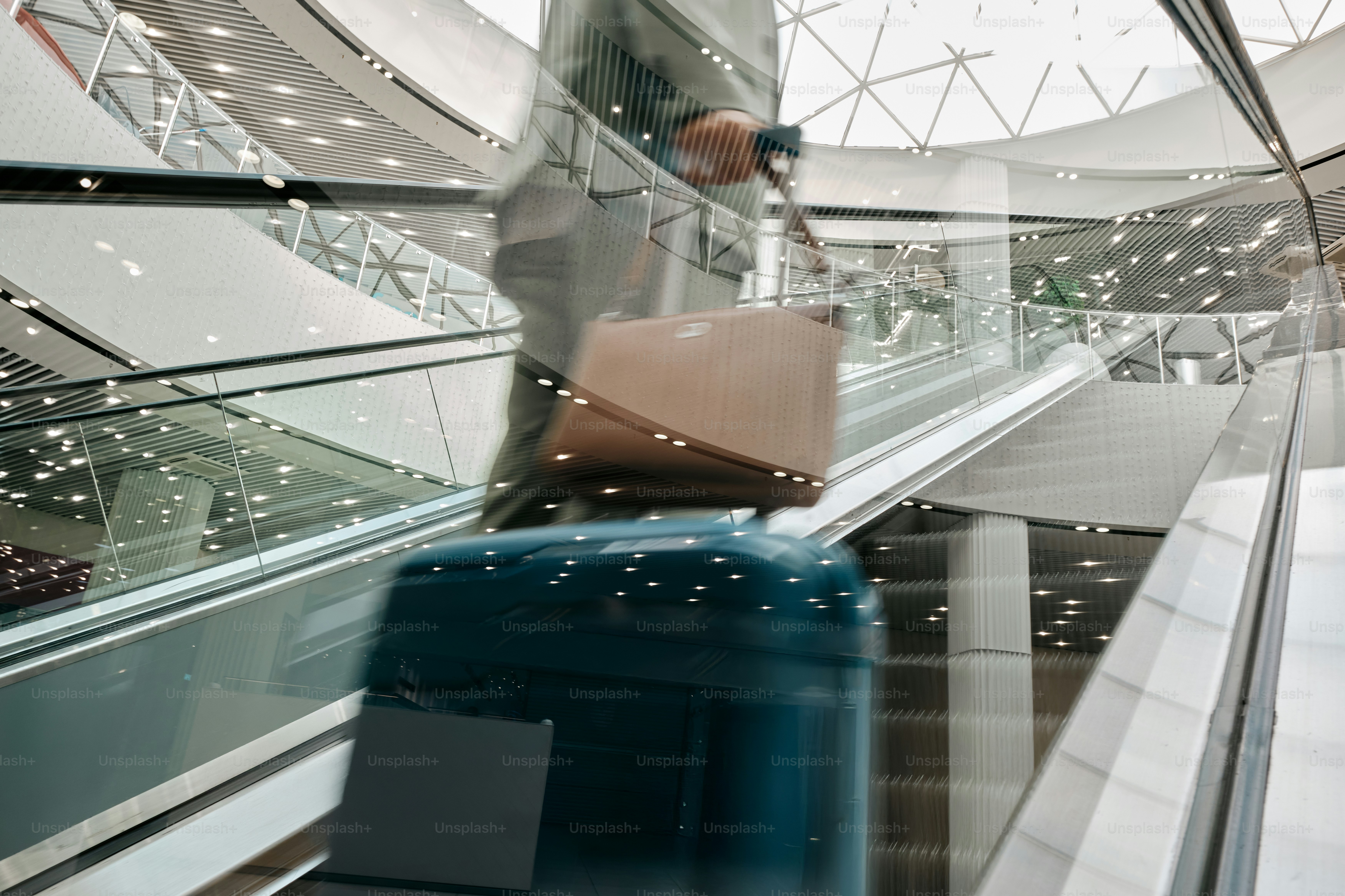 A man walking down an escalator carrying a suitcase