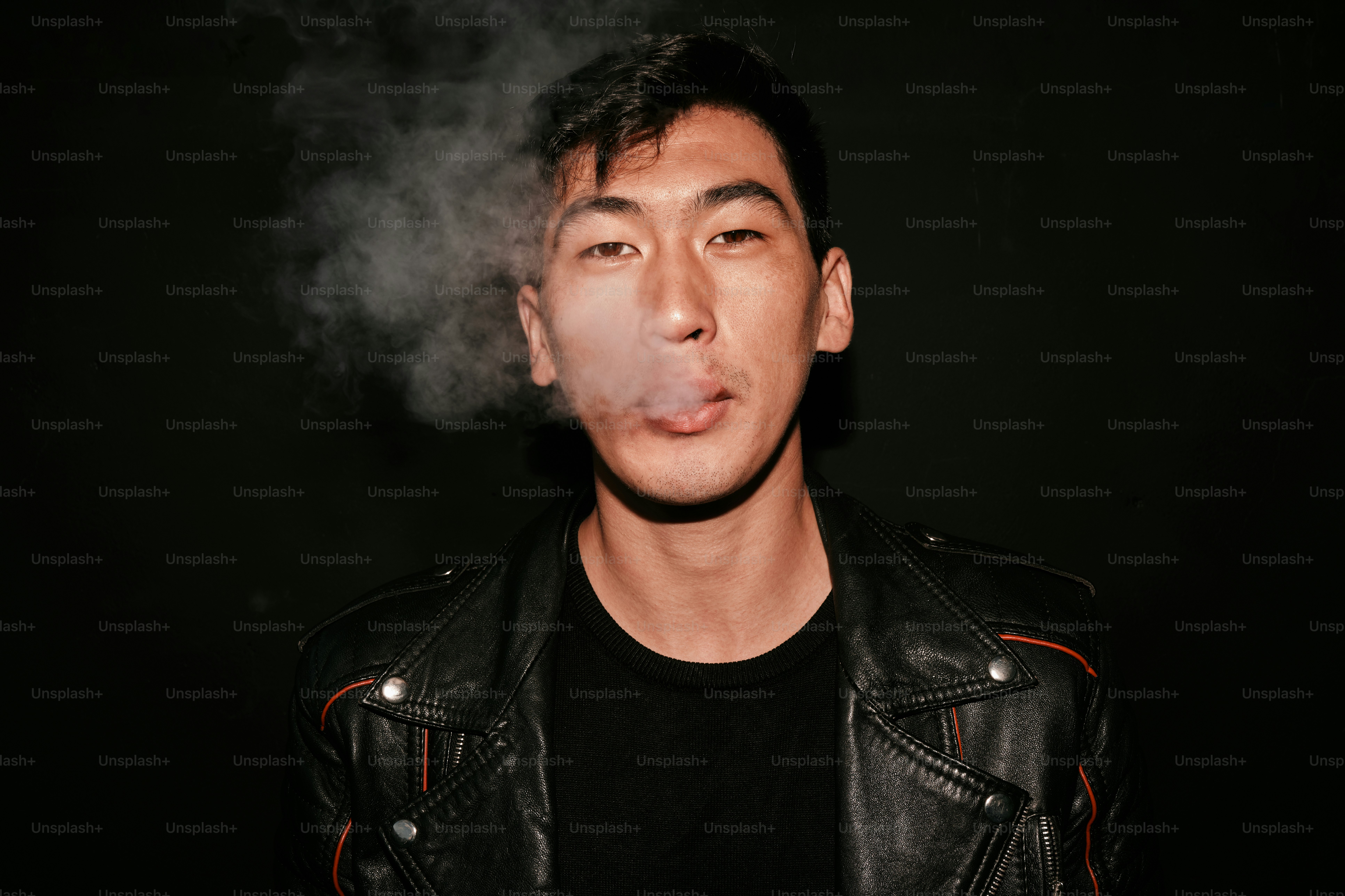 A man in a leather jacket smoking a cigarette