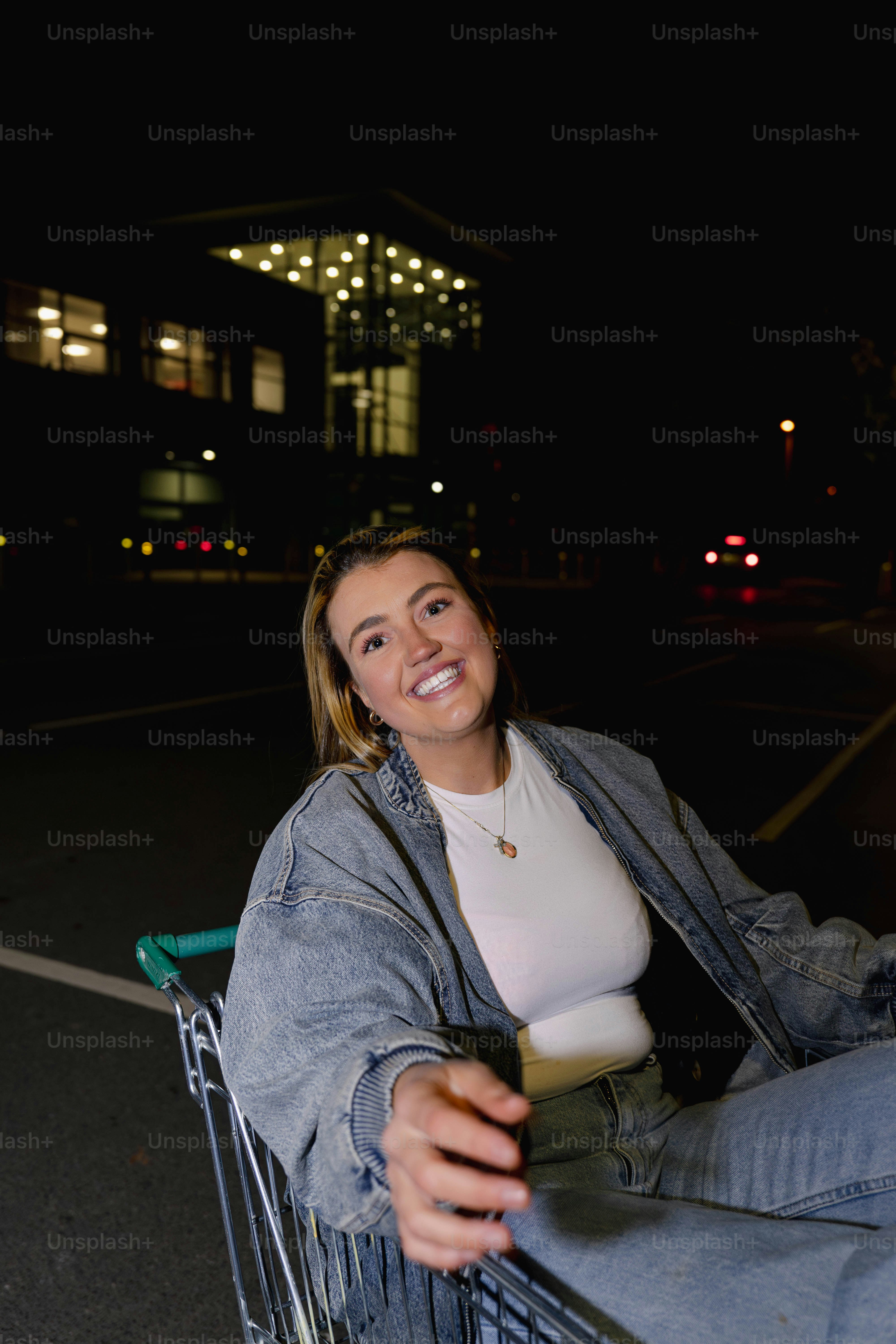 A woman sitting in a shopping cart holding a drink