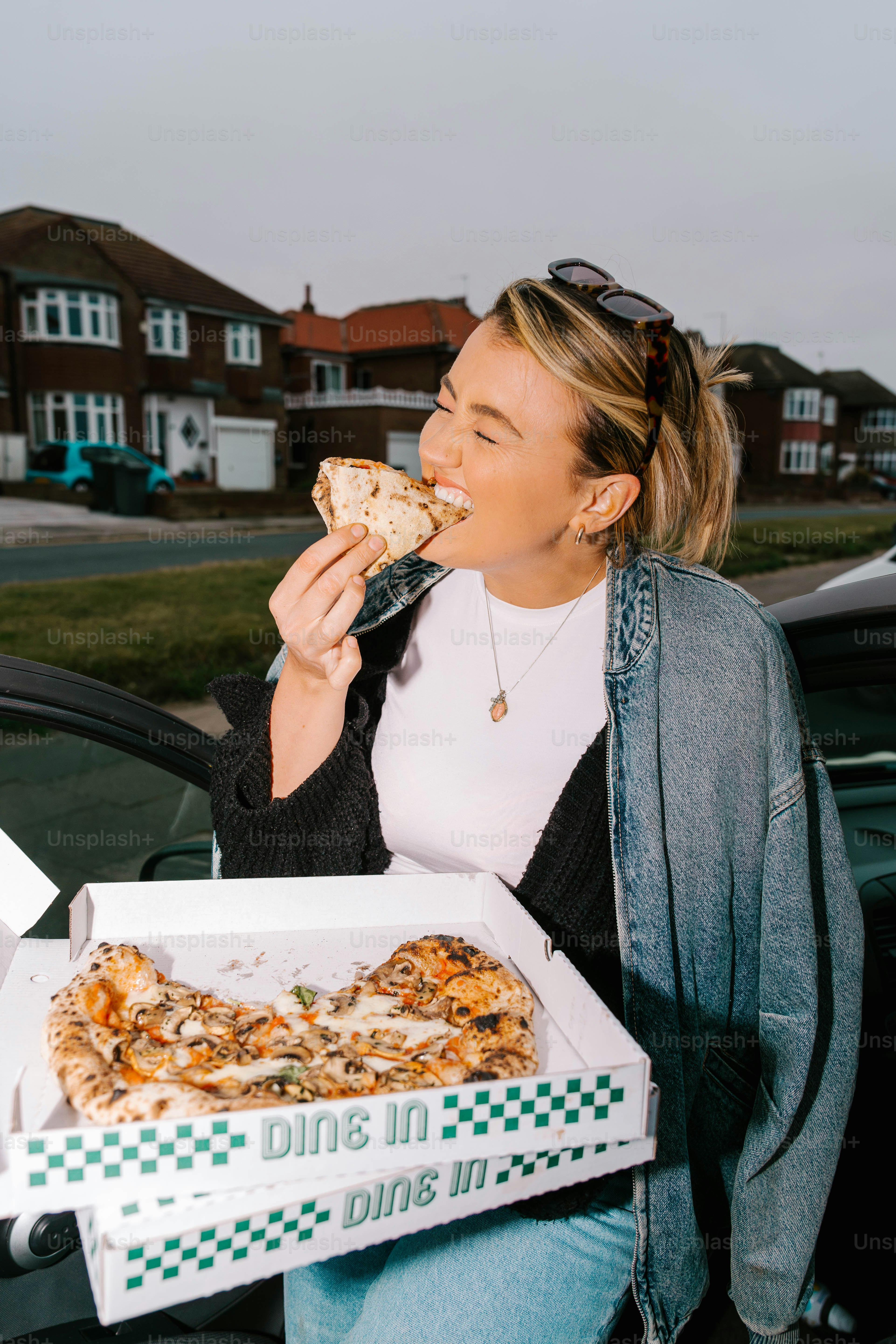 A woman eating a slice of pizza from a box