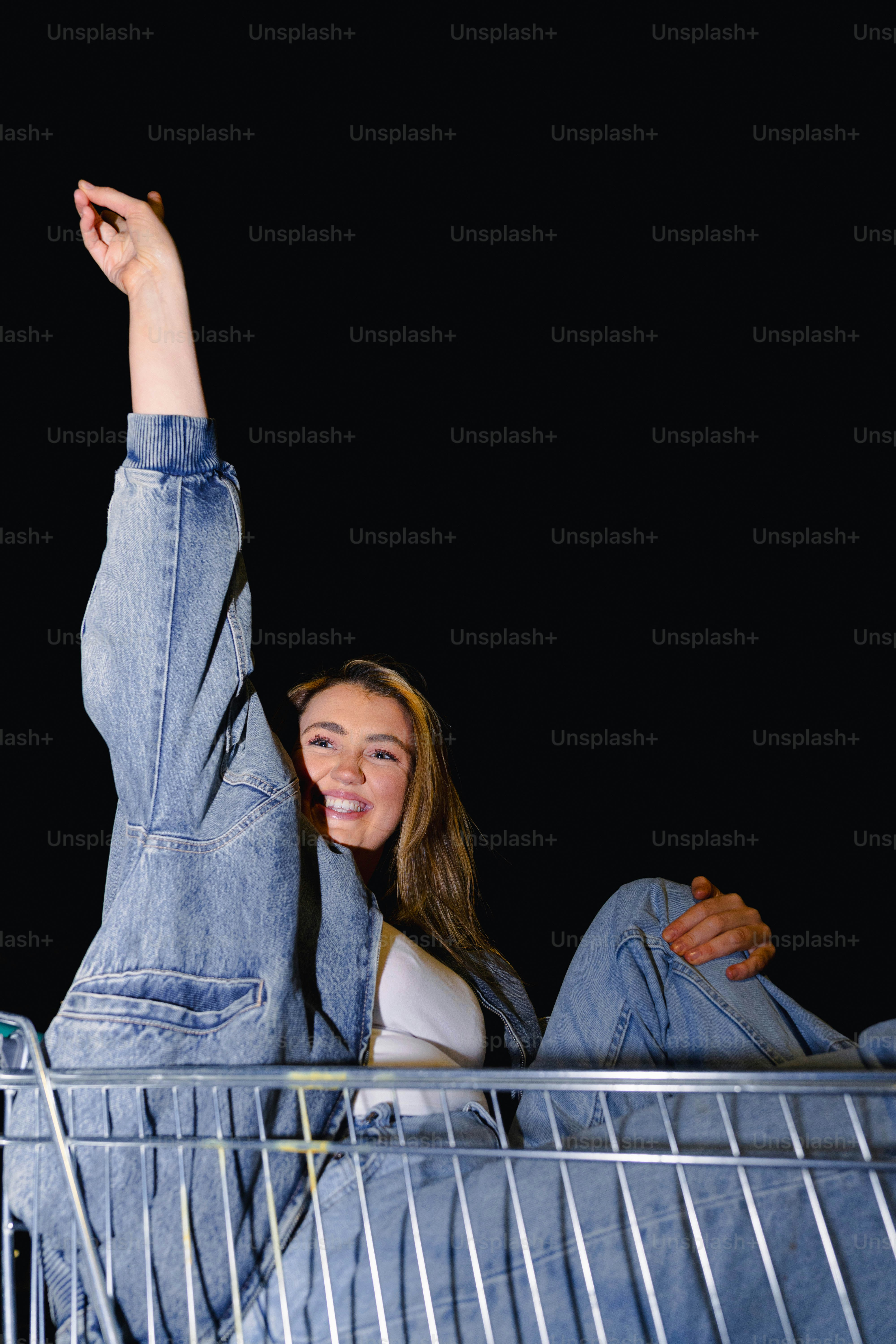 A woman laying on top of a shopping cart