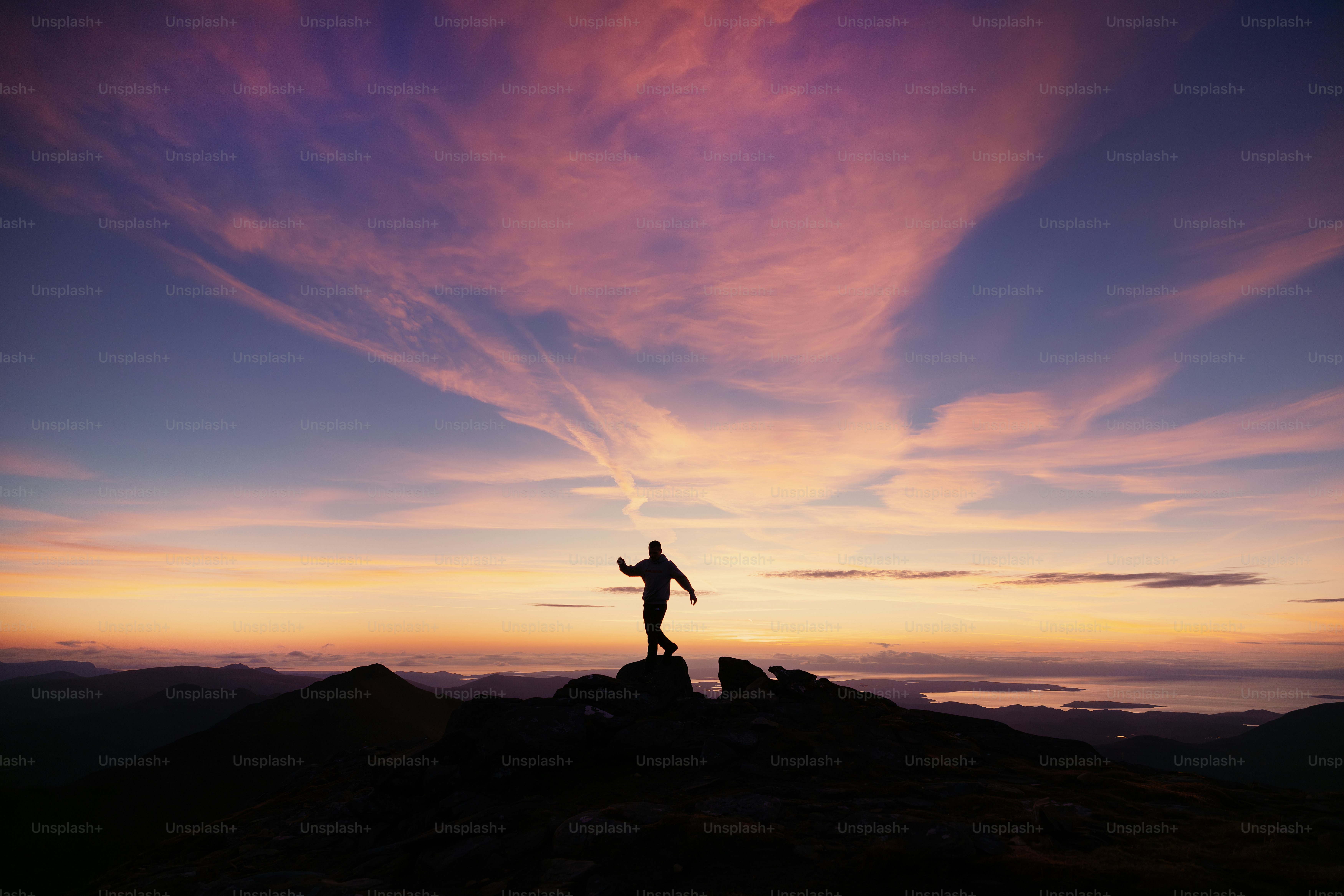 Uma pessoa em pé no topo de uma montanha ao pôr do sol