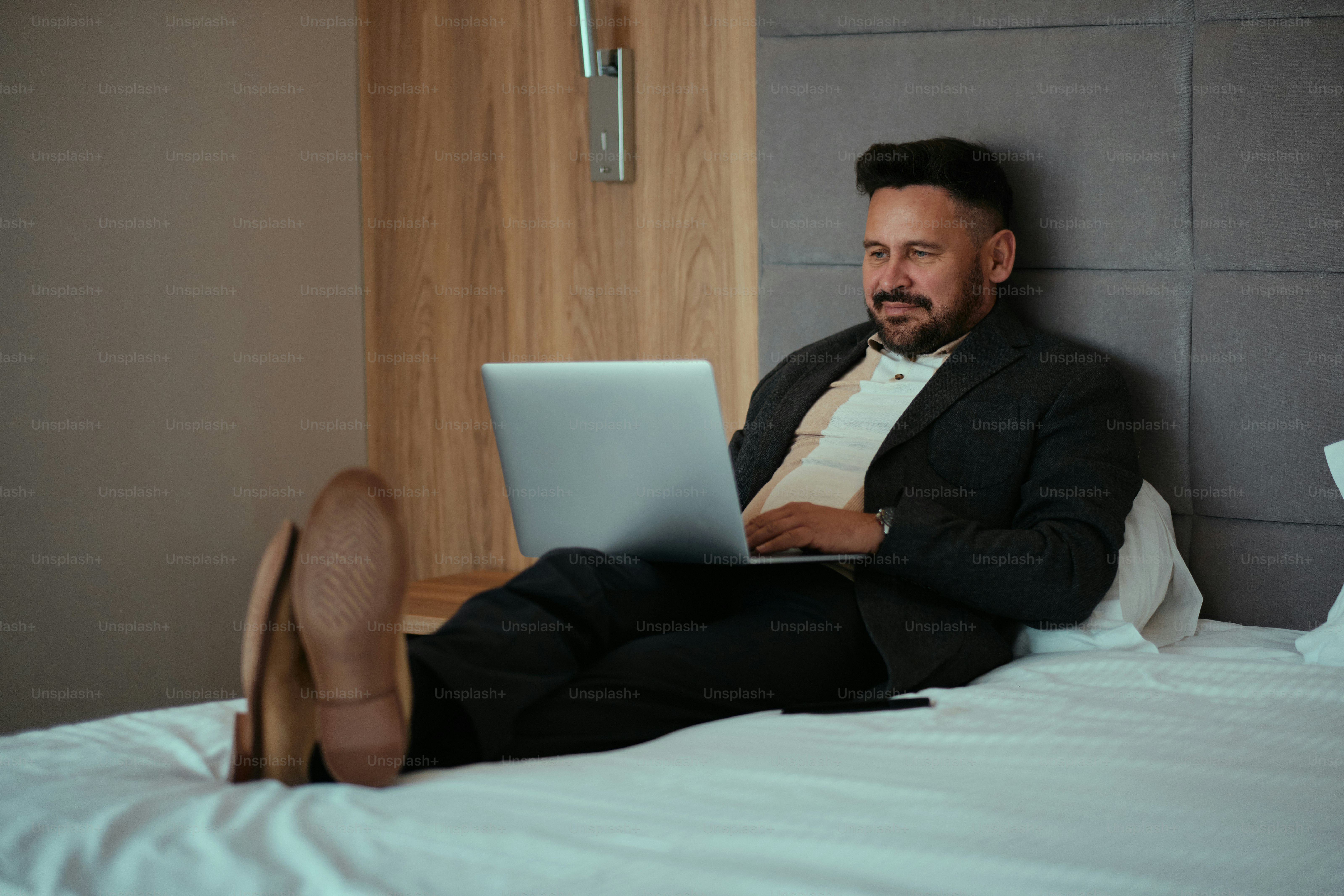 Ein Mann, der mit einem Laptop auf einem Bett sitzt