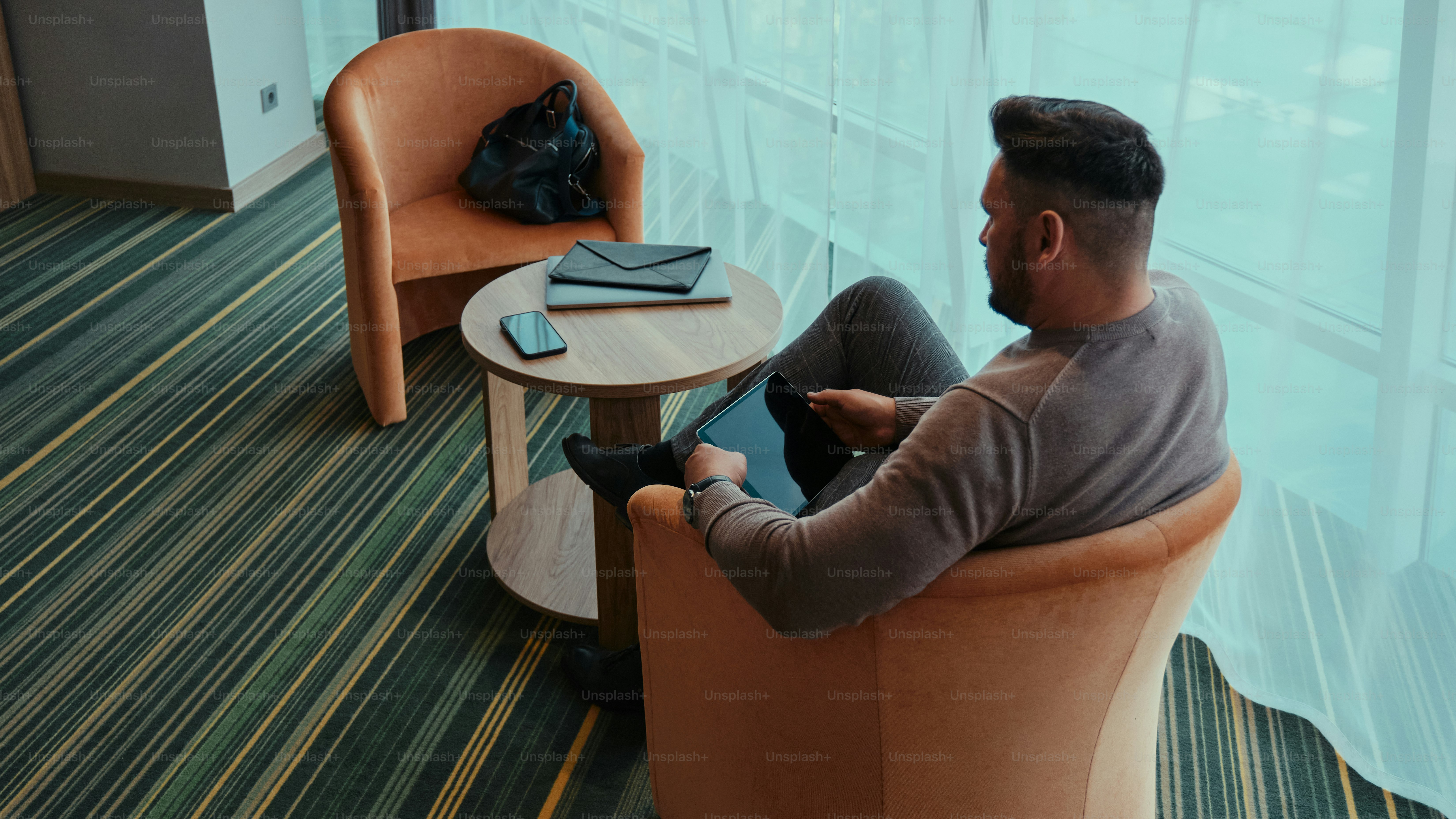 Ein Mann sitzt auf einem Stuhl und schaut auf ein Tablet