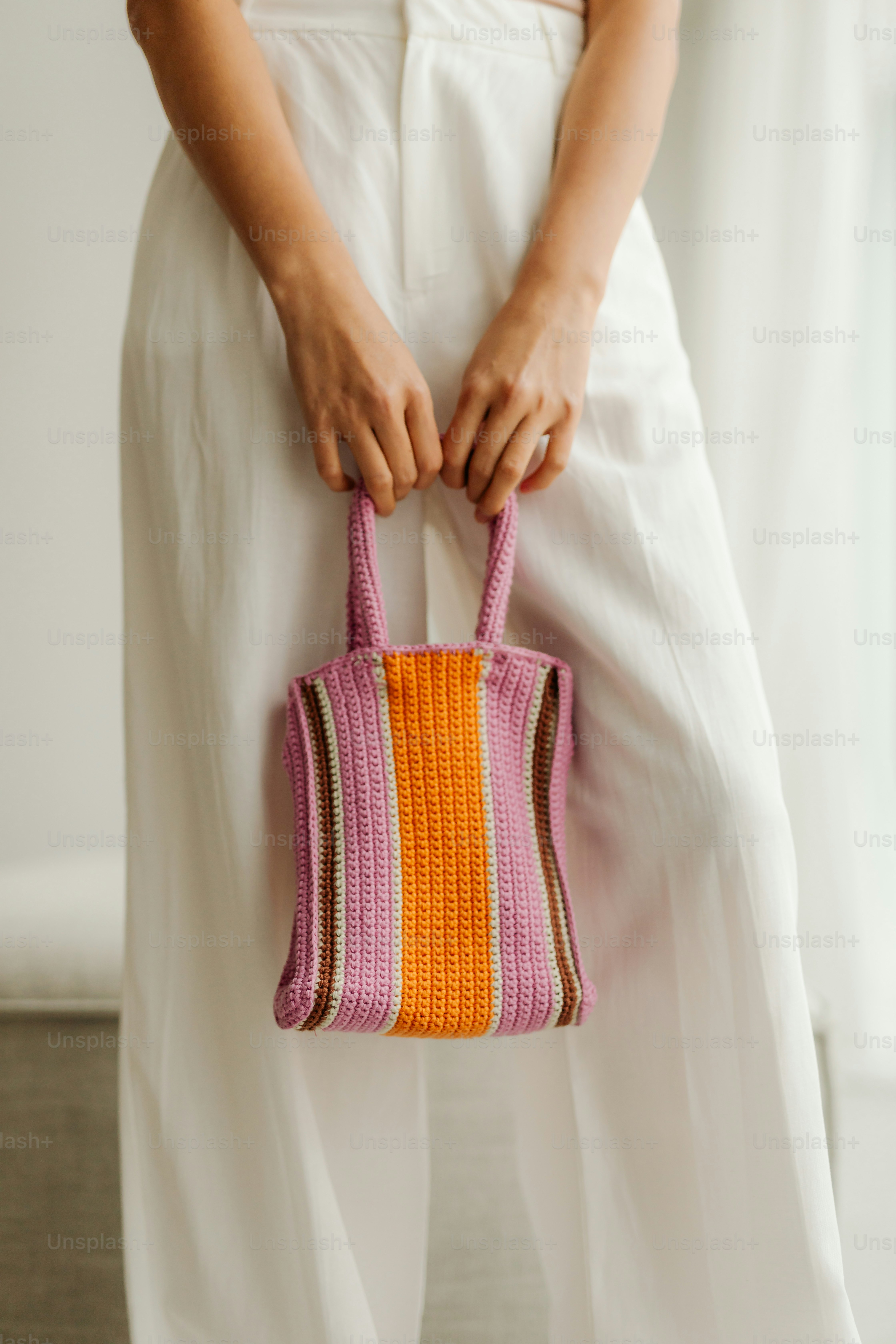 A woman holding a pink and orange purse