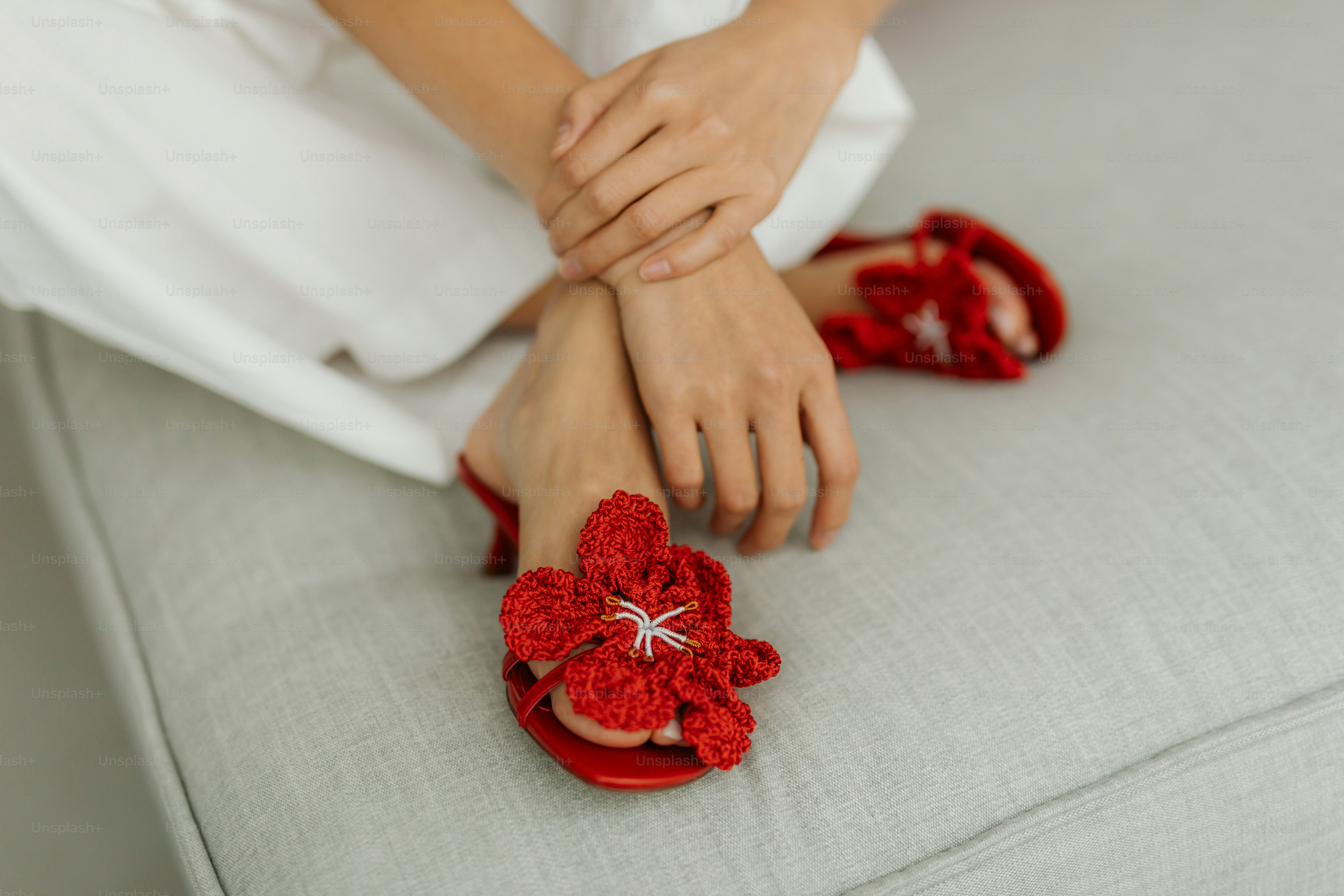 A woman sitting on a couch wearing red slippers