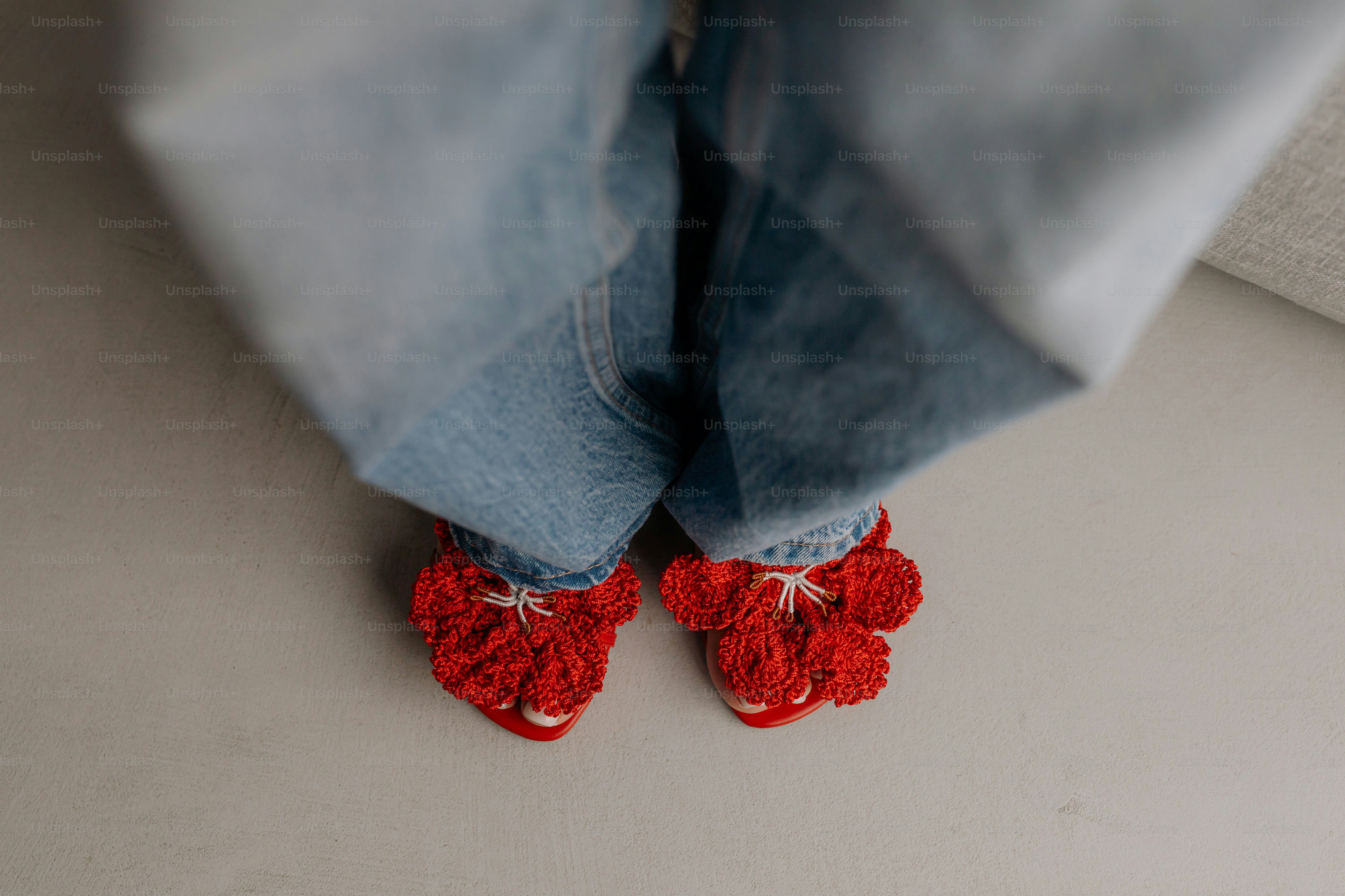 Un primo piano dei piedi di una persona che indossa scarpe rosse all'uncinetto
