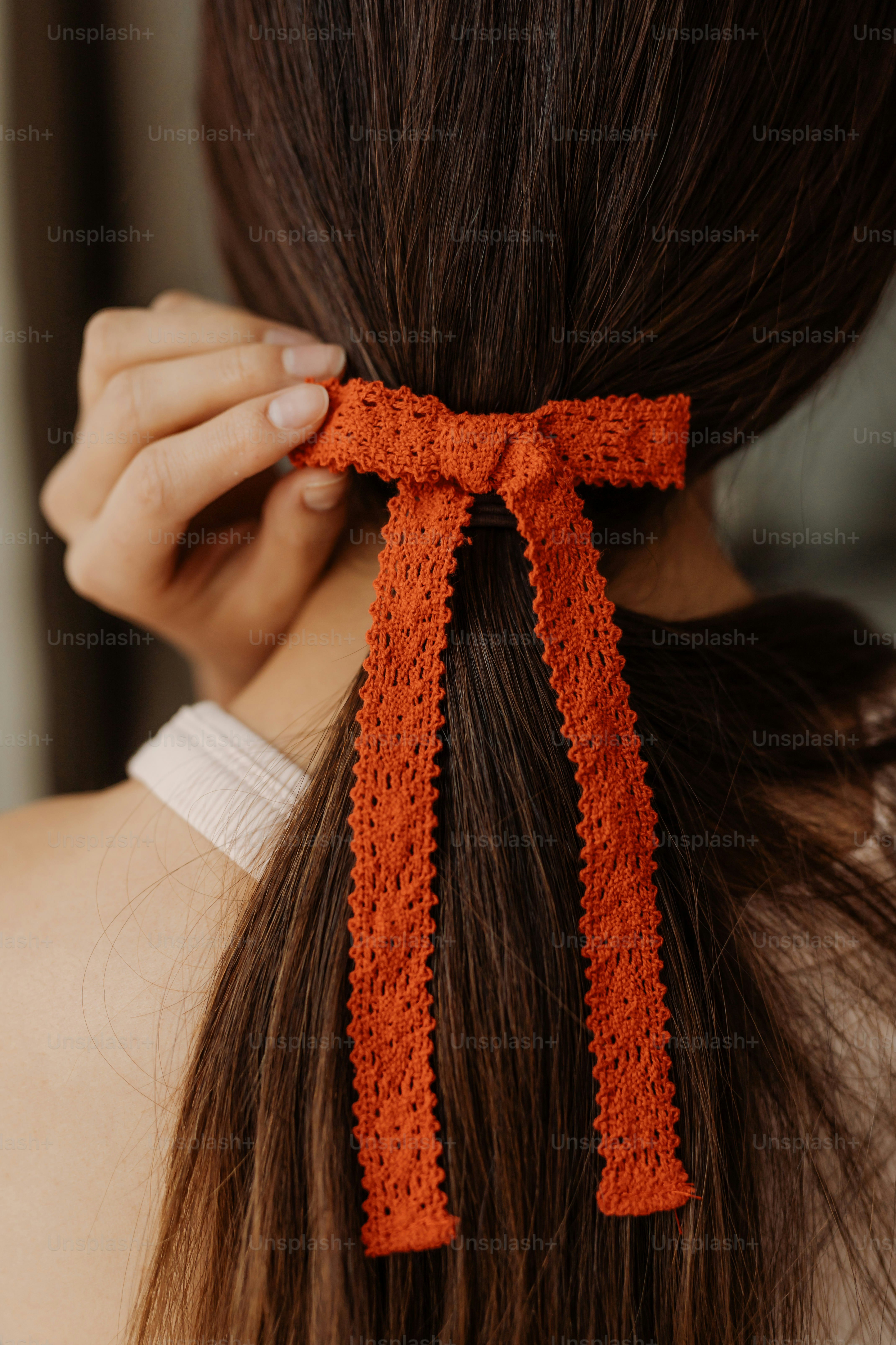 A woman wearing an orange crochet hair tie