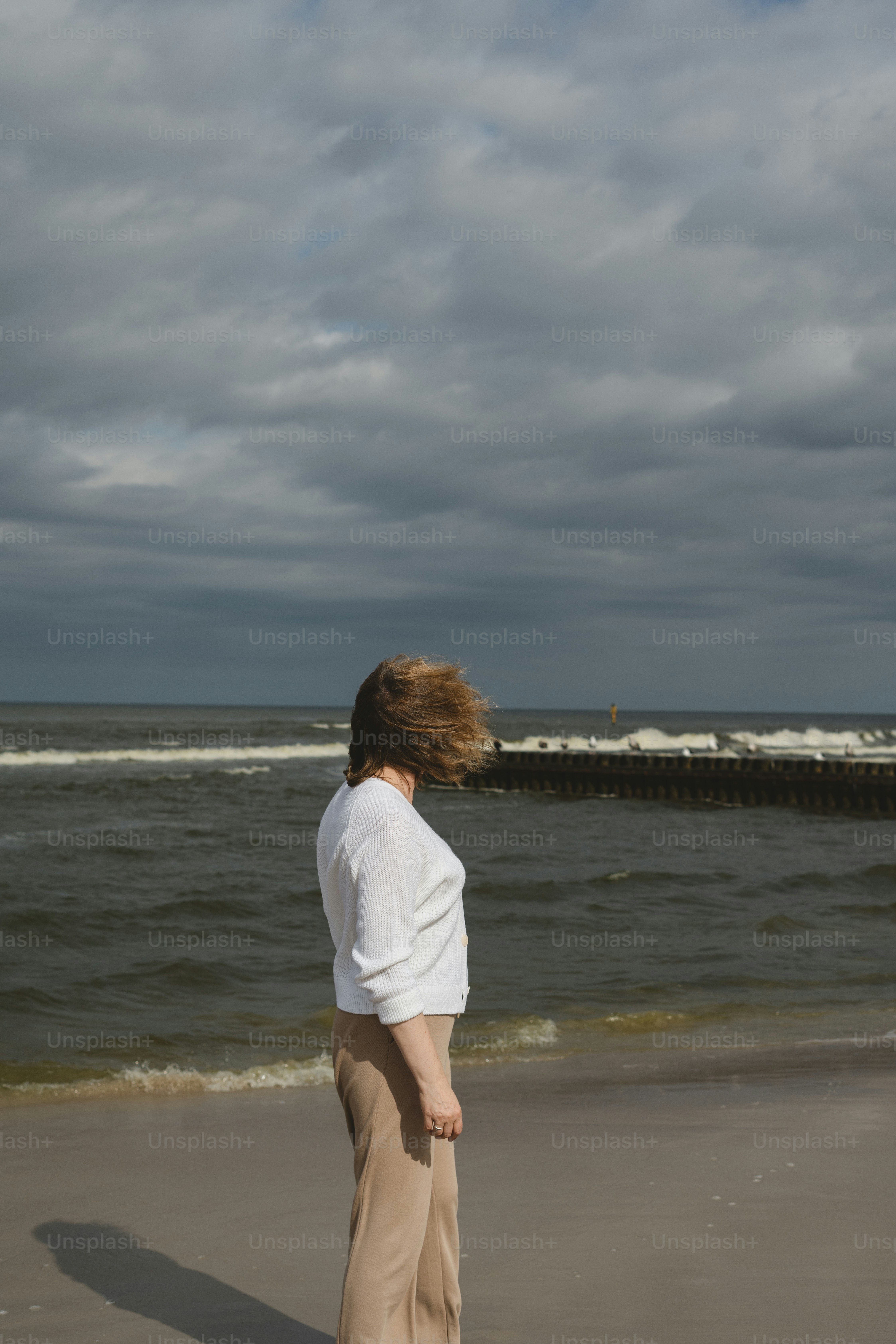 A woman standing on top of a beach next to the ocean