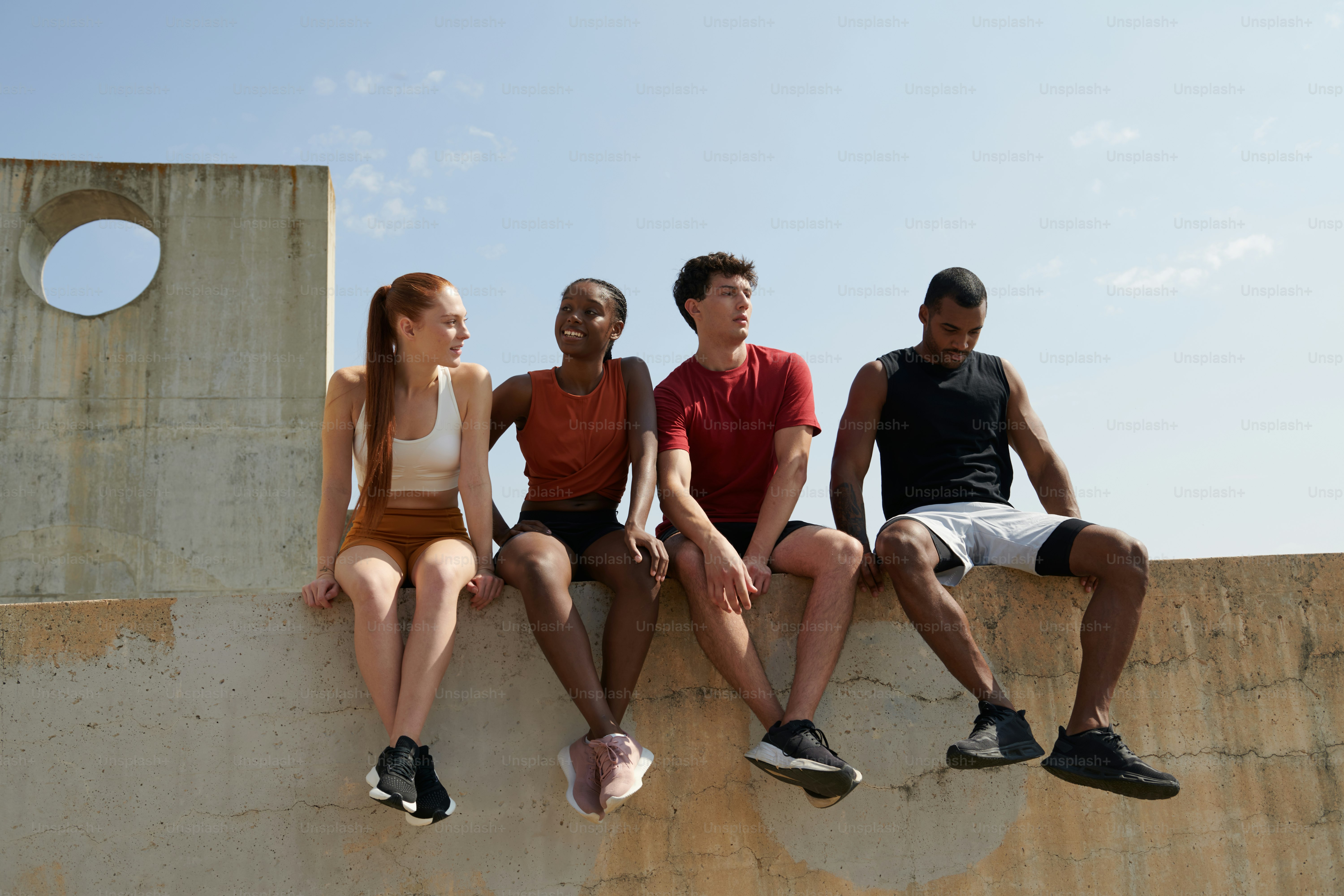 A group of people sitting on top of a cement wall