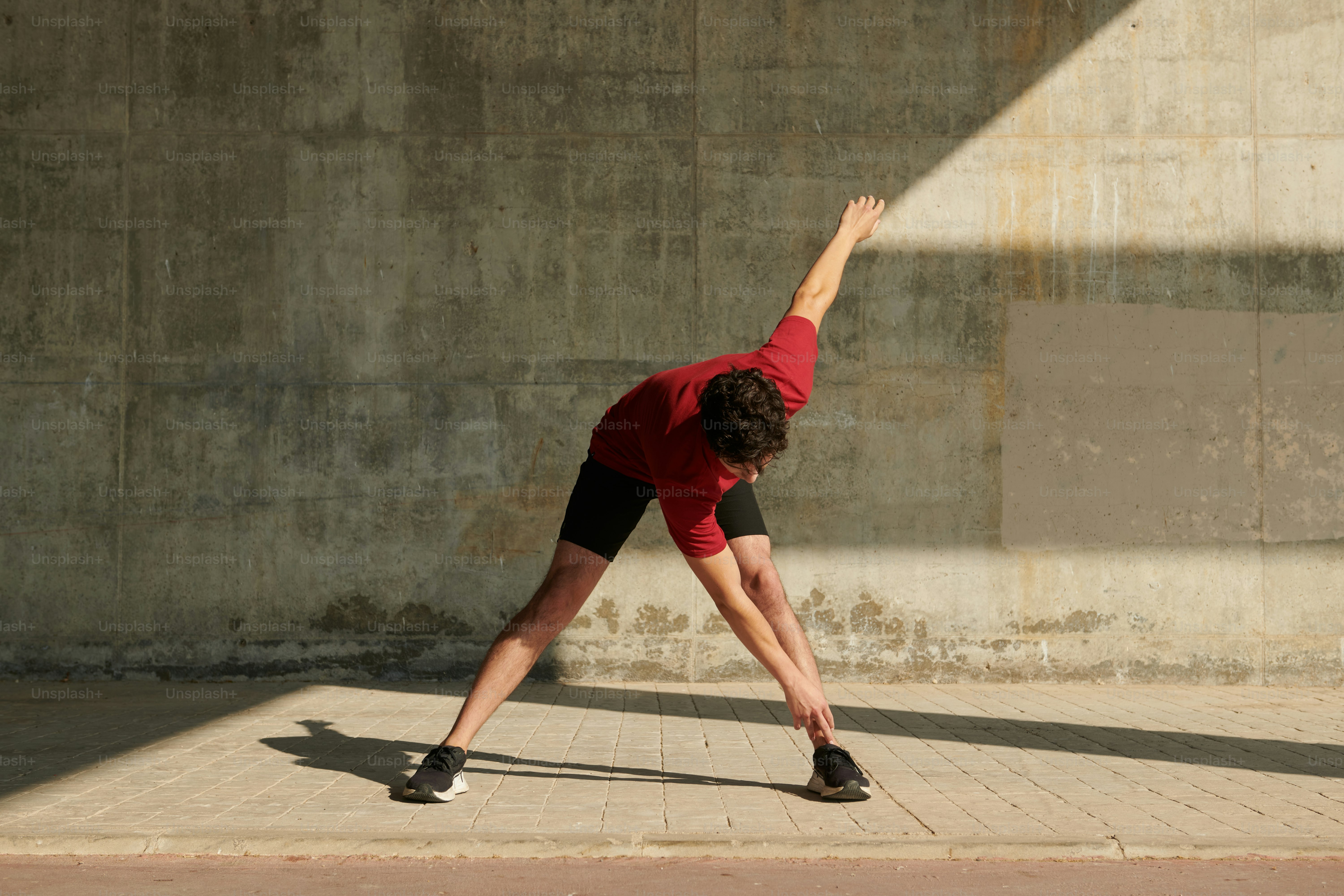 A woman in a red shirt and black shorts doing a handstand