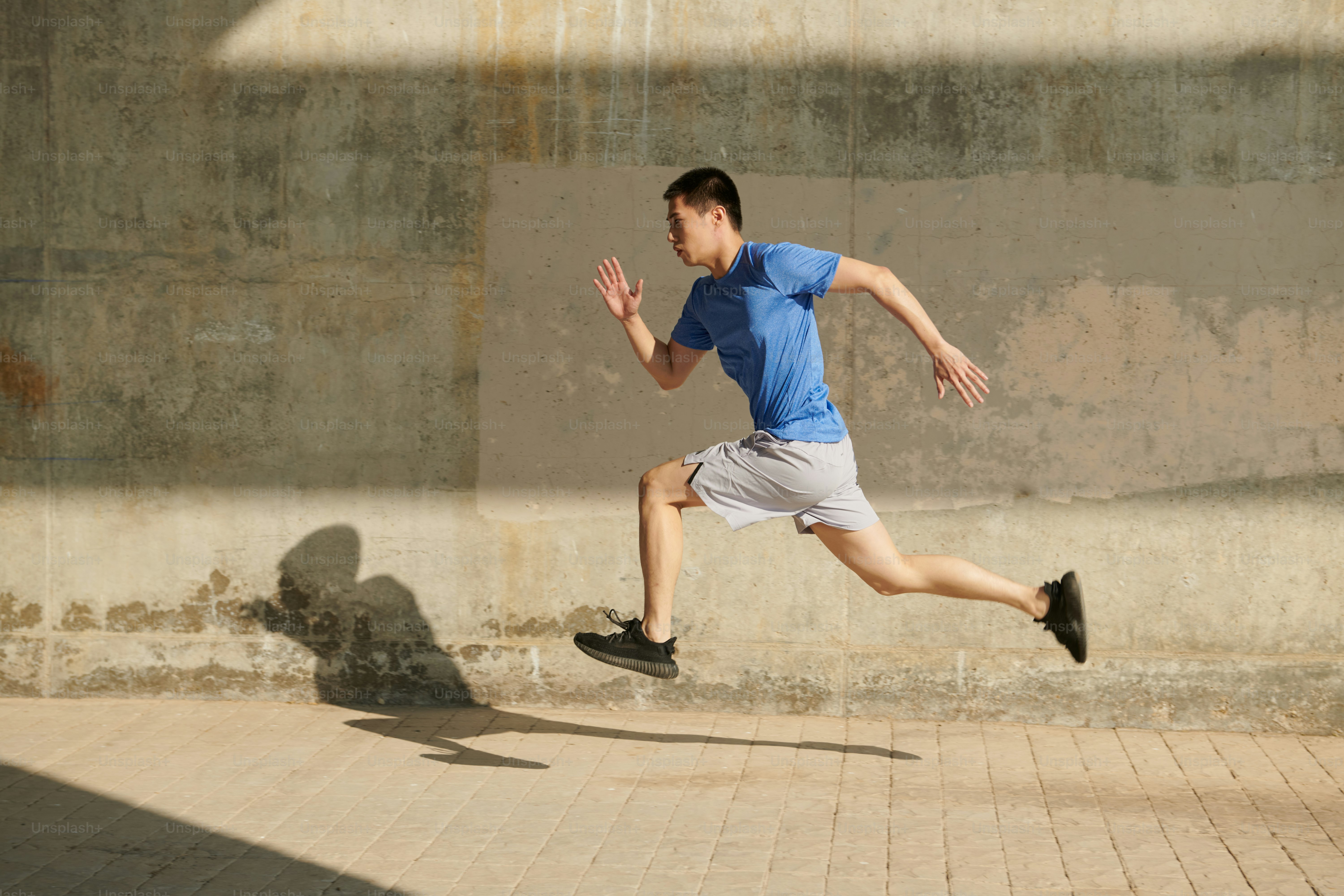 A man running down a sidewalk in a blue shirt