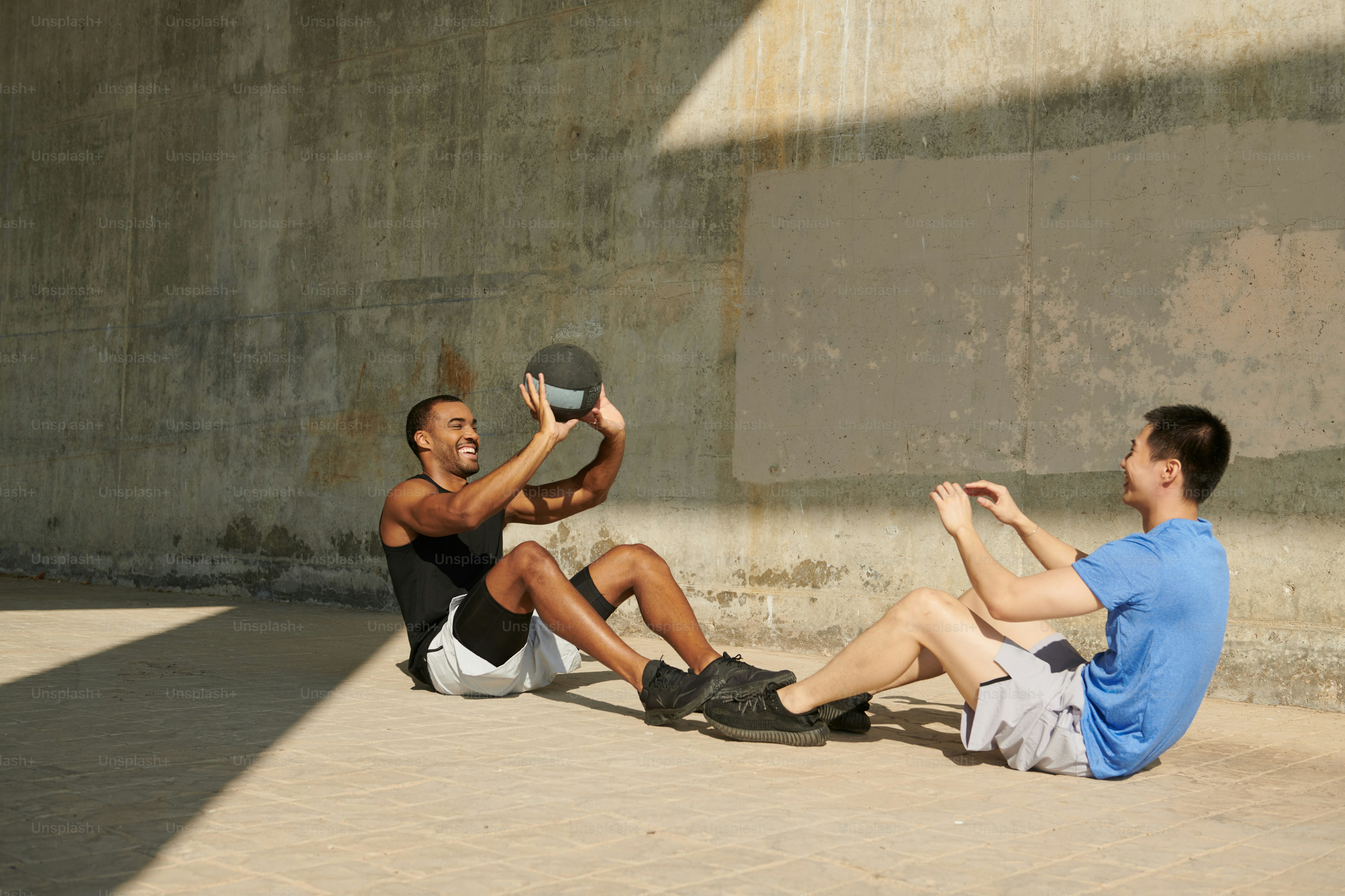 Two men sitting on the ground playing with a frisbee