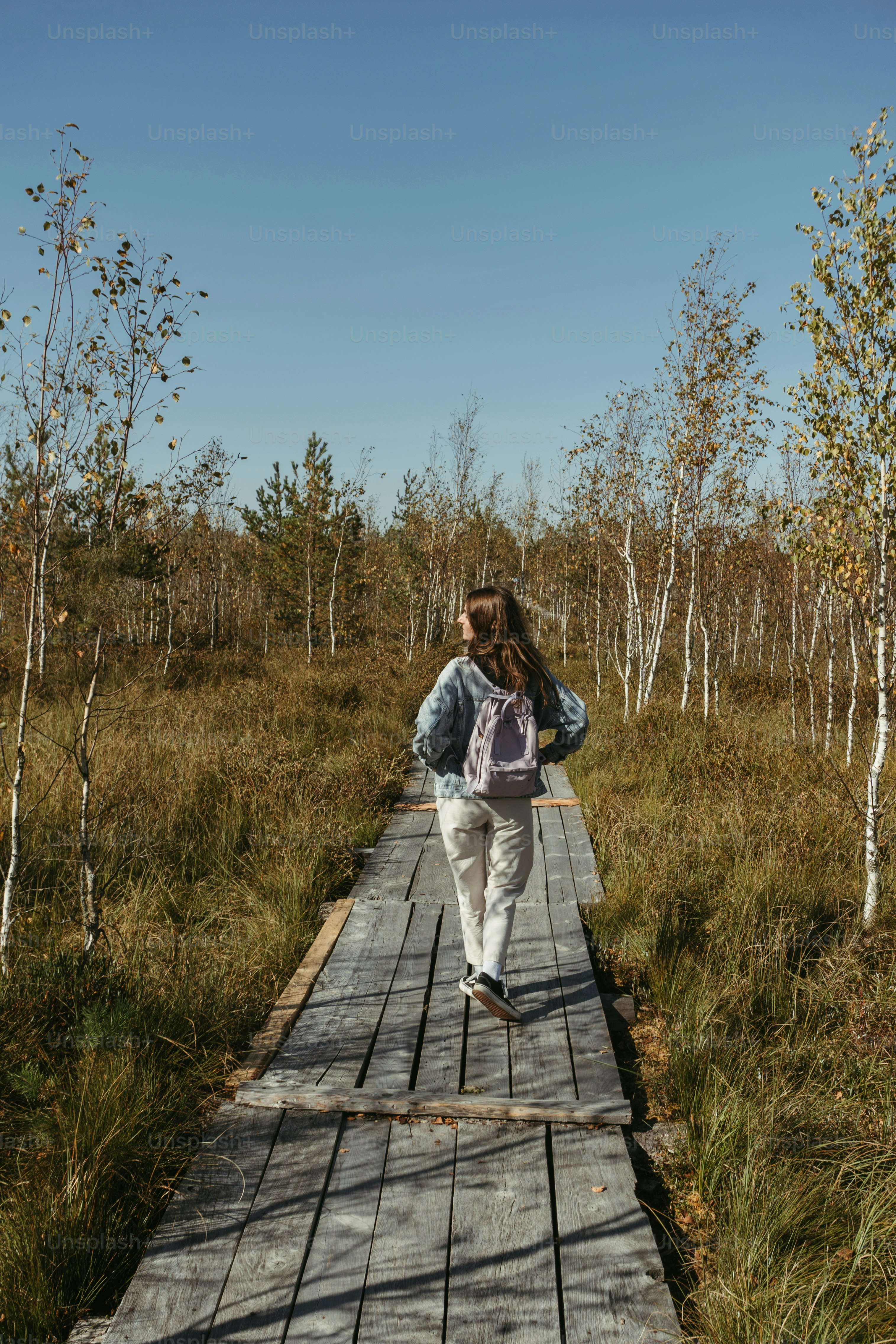 A woman walking across a wooden bridge in the woods