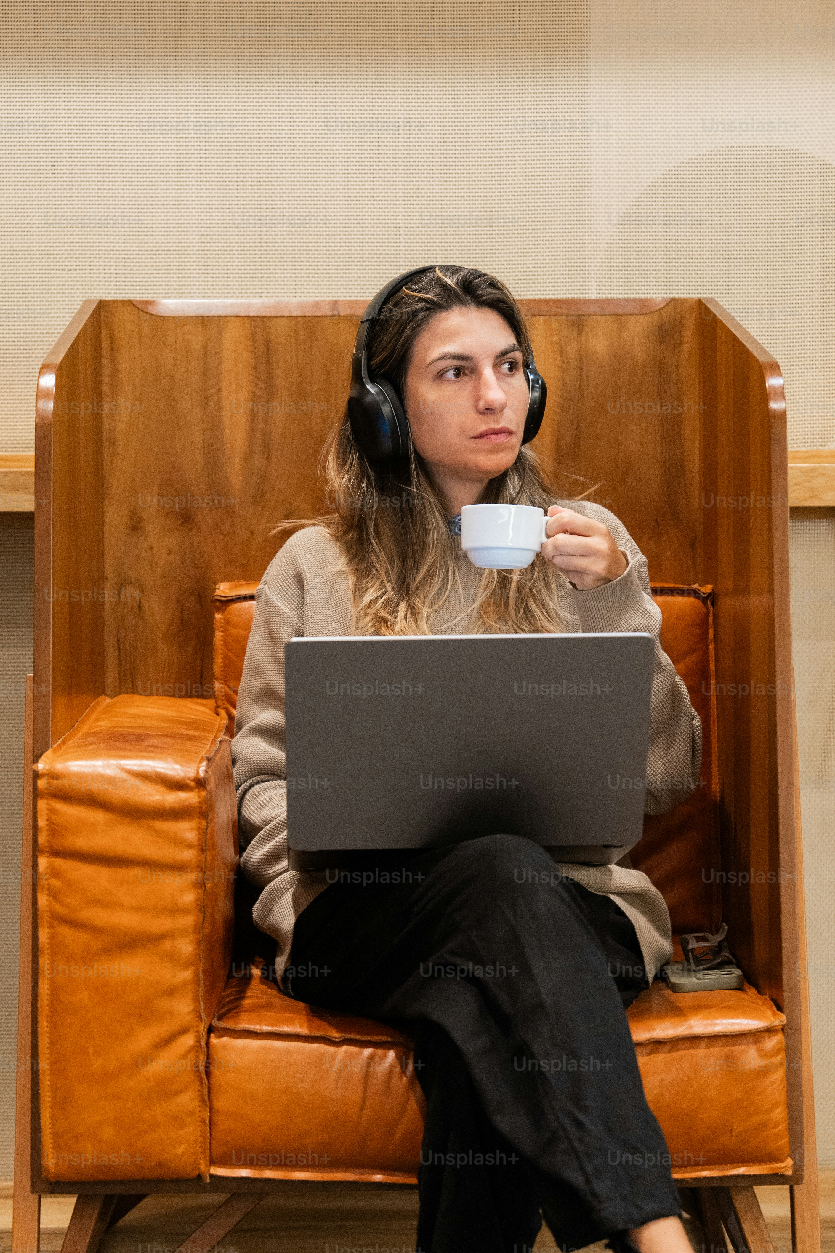 A woman sitting in a chair with a laptop and headphones