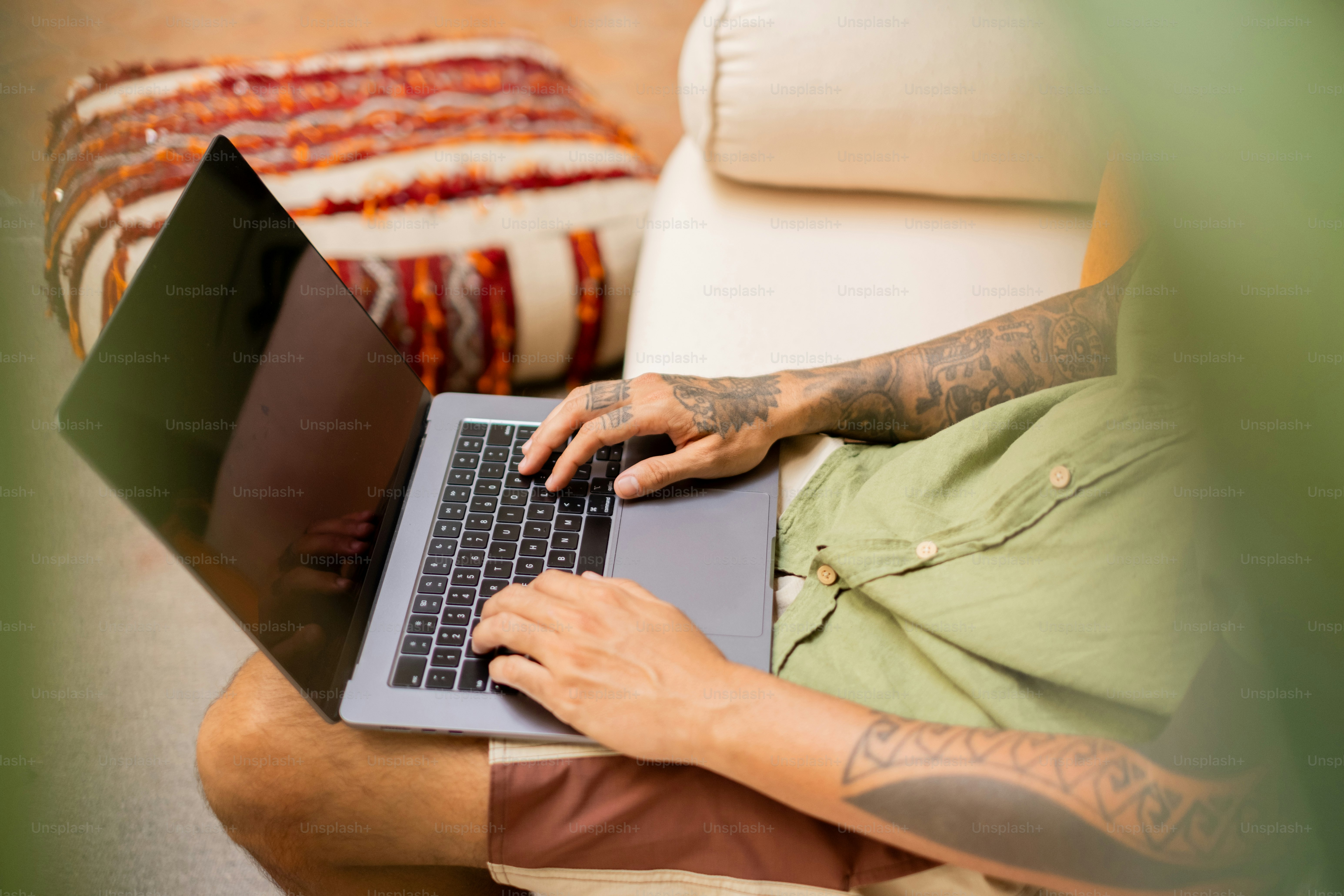 A man sitting on a couch using a laptop computer