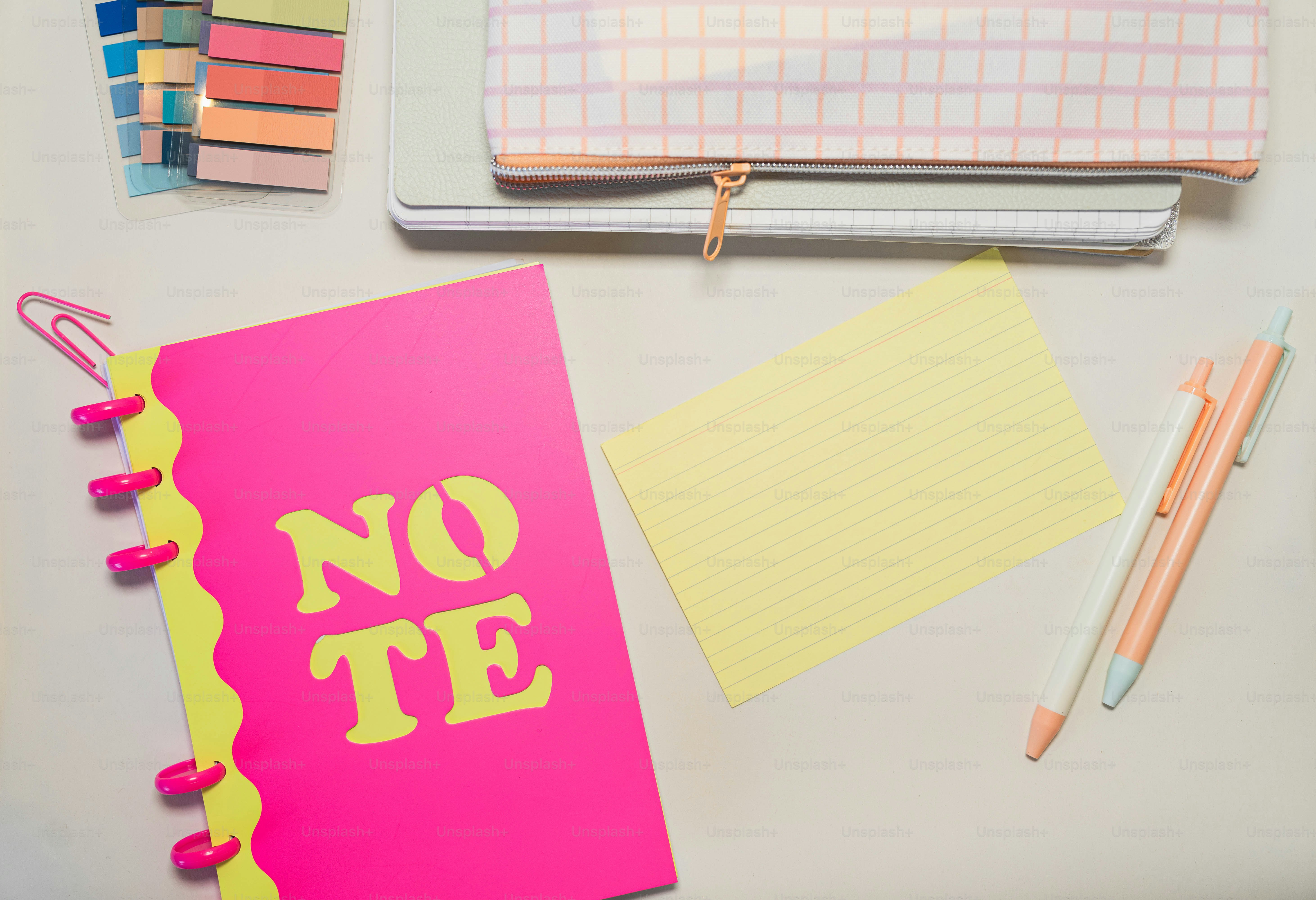 A desk with notebooks, pens, and a notepad