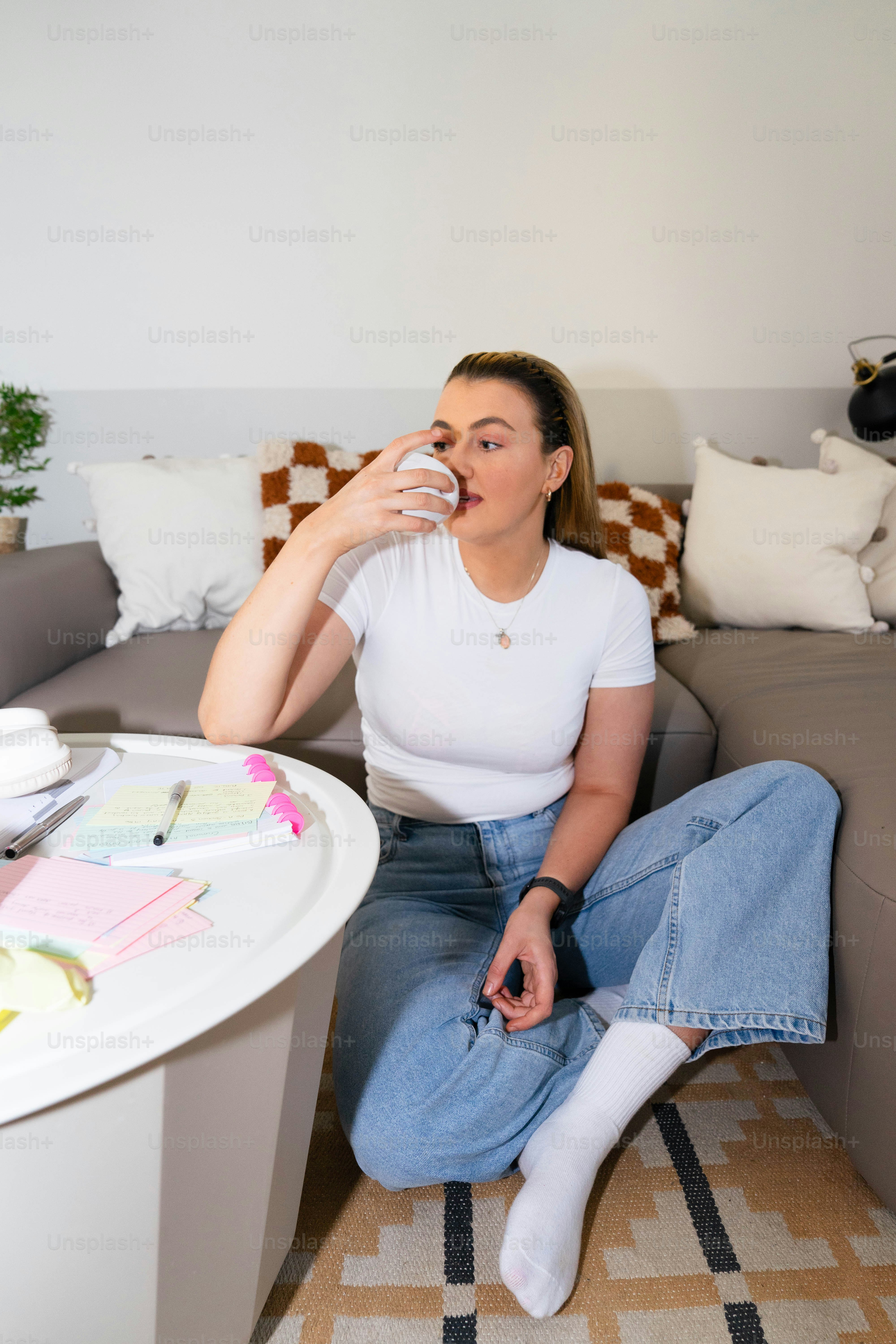 A woman sitting on a couch drinking from a glass
