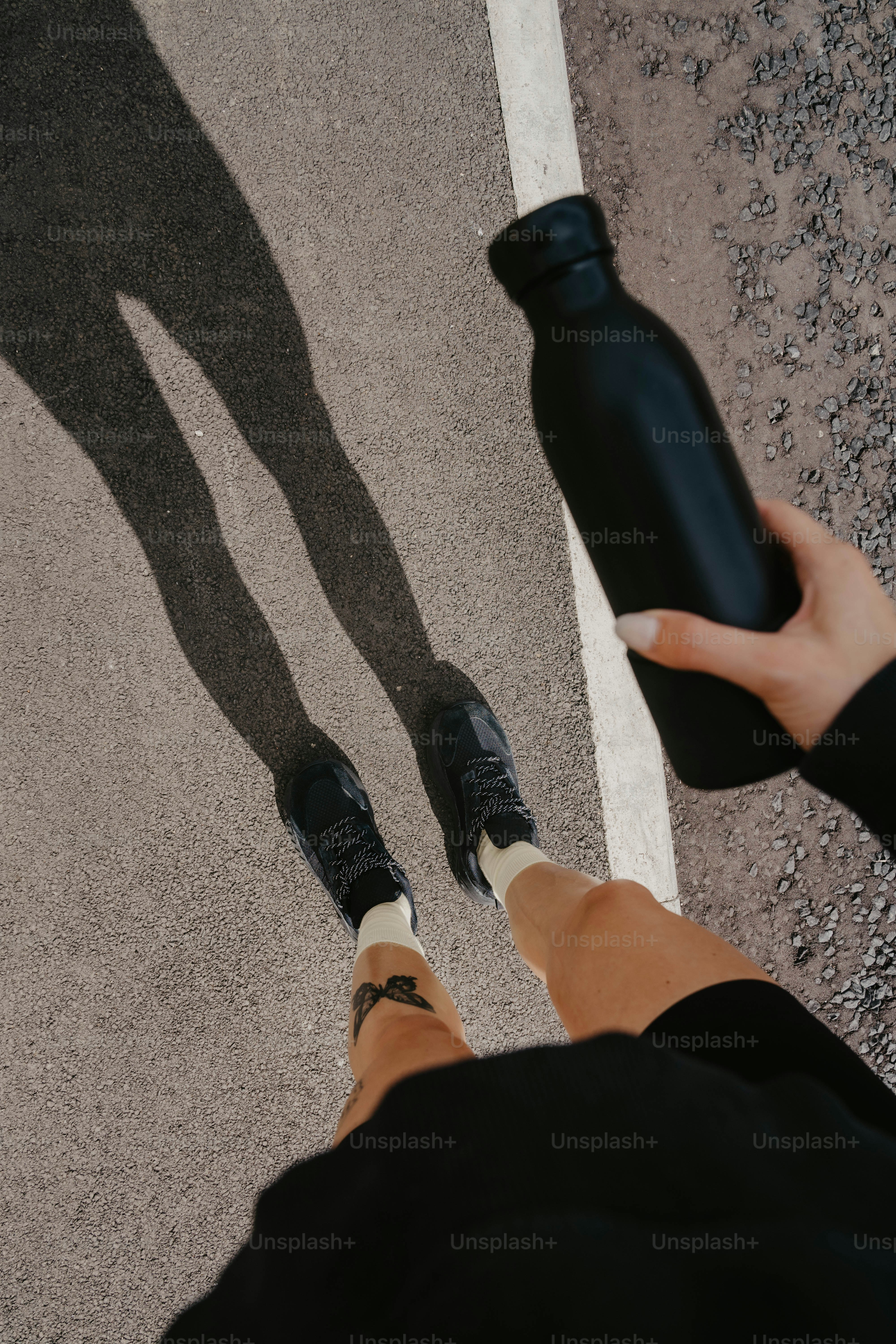 A person standing in the middle of a street with their shadow on the ground