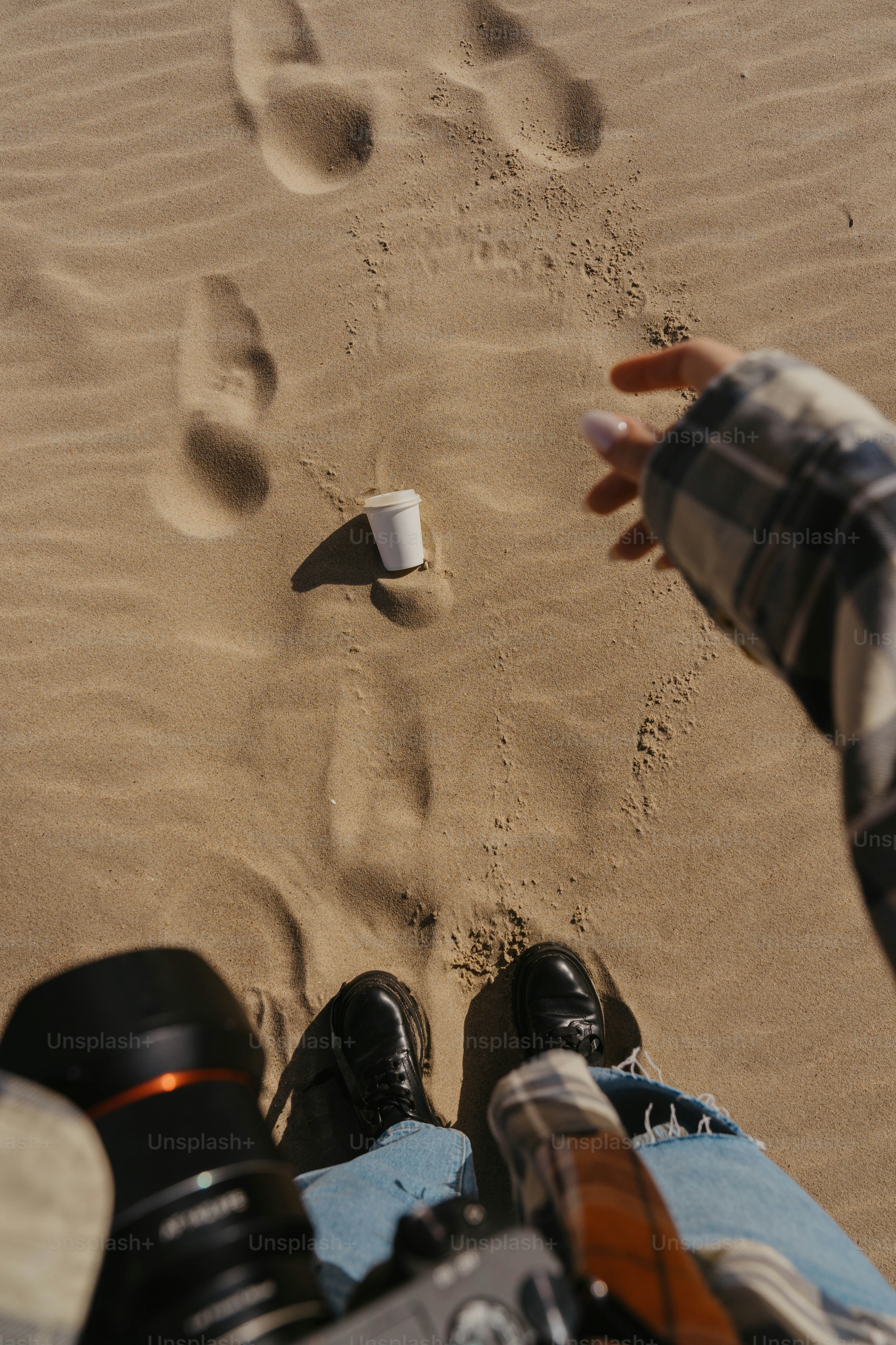 A person sitting in the sand with their feet in the sand