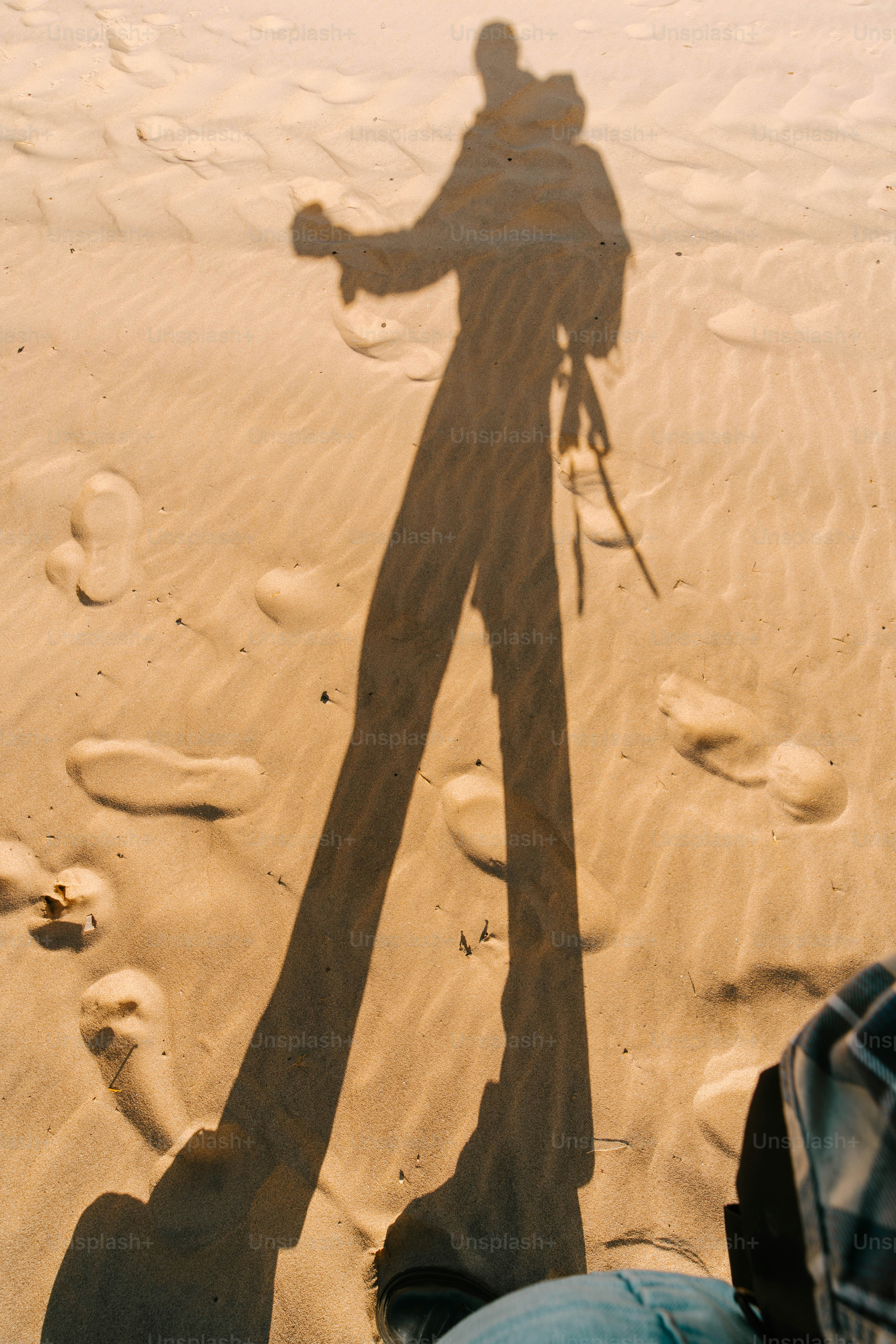 A shadow of a person standing in the sand