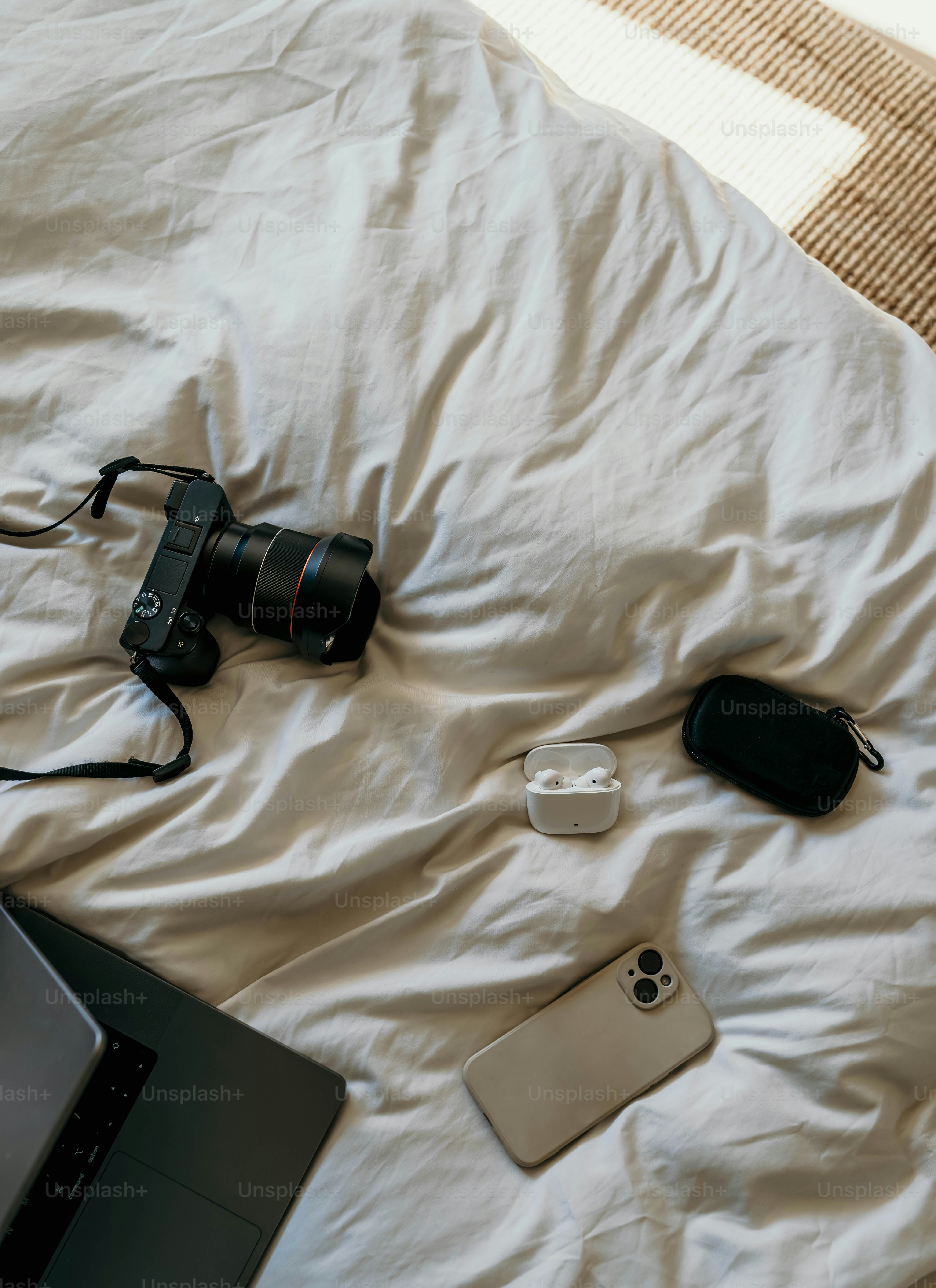 A bed with a laptop, camera, and other items on it