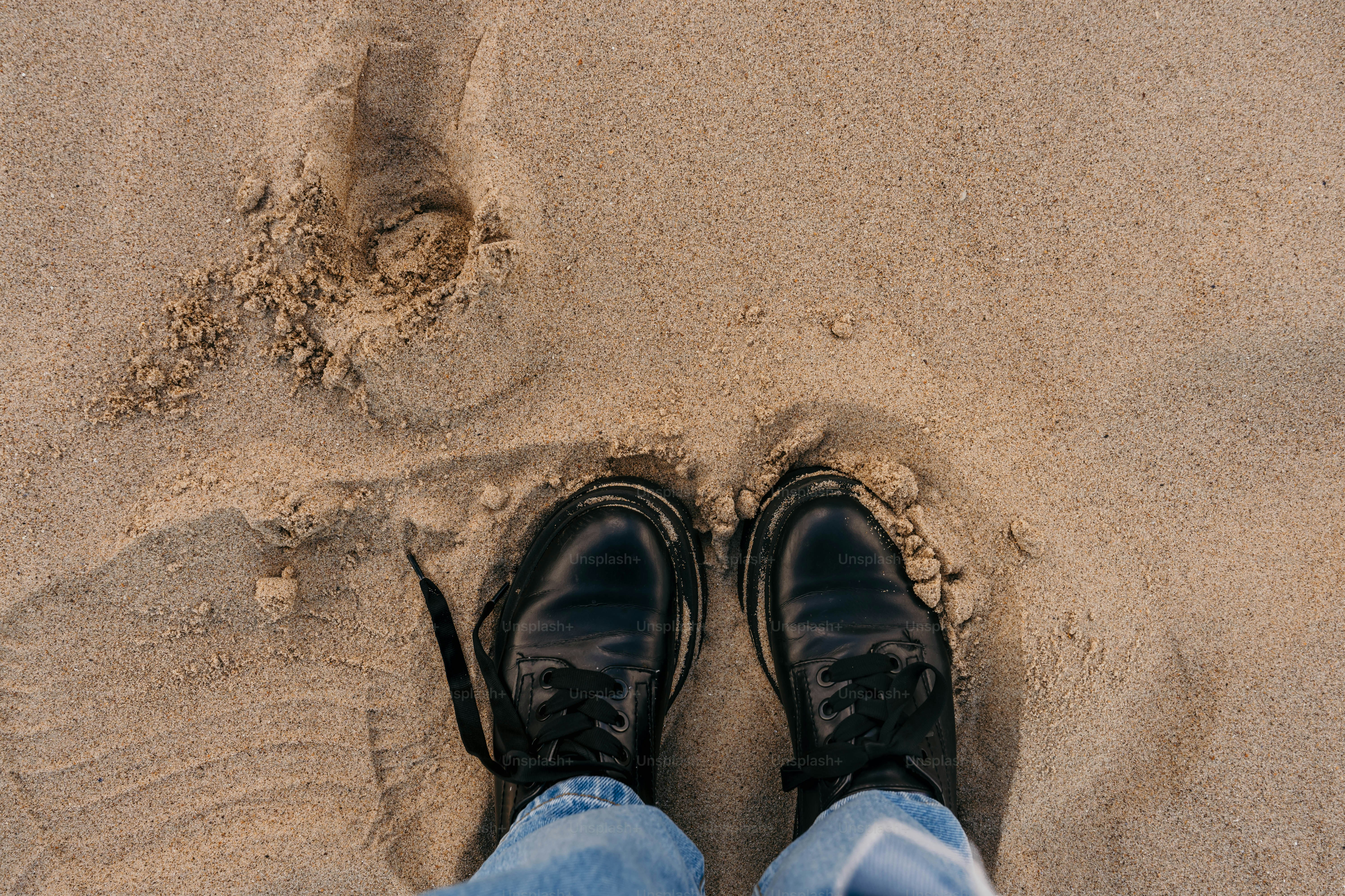 A person standing in the sand with their feet in the sand