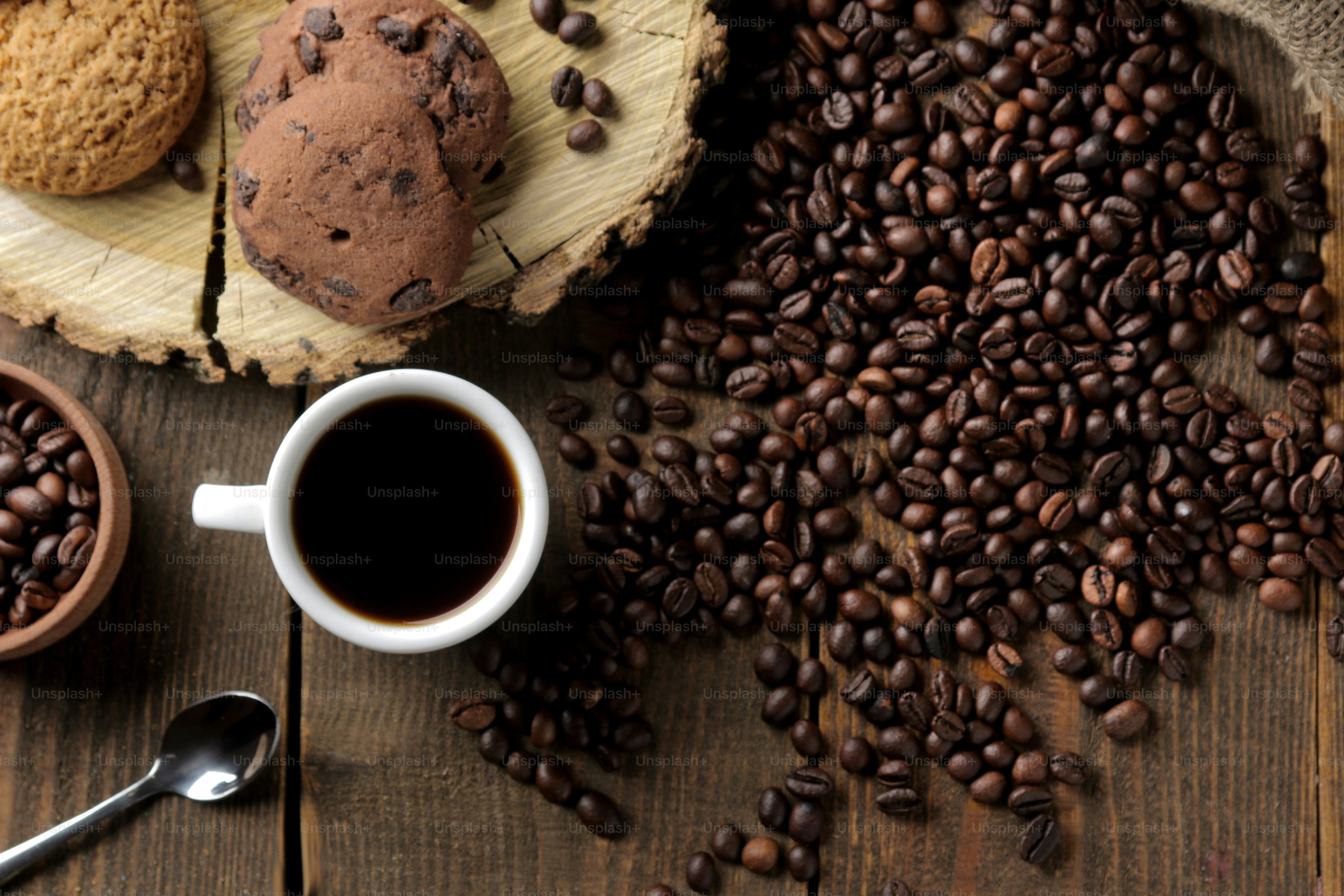 Roasted coffee grains and a cup of coffee and cookies on a brown wooden background. Robusta, Arabica. top view