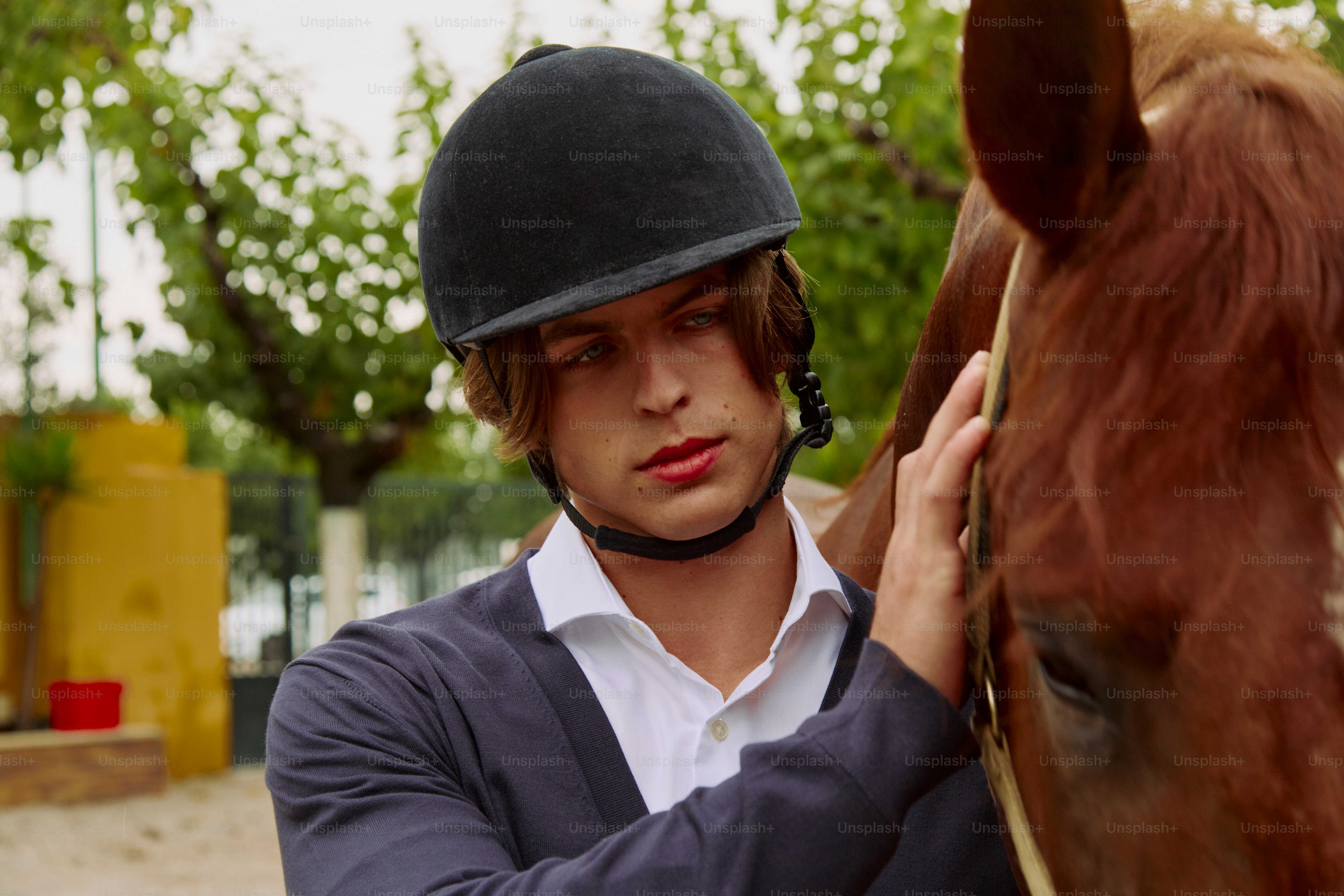 Ein Mann mit Helm streichelt ein Pferd