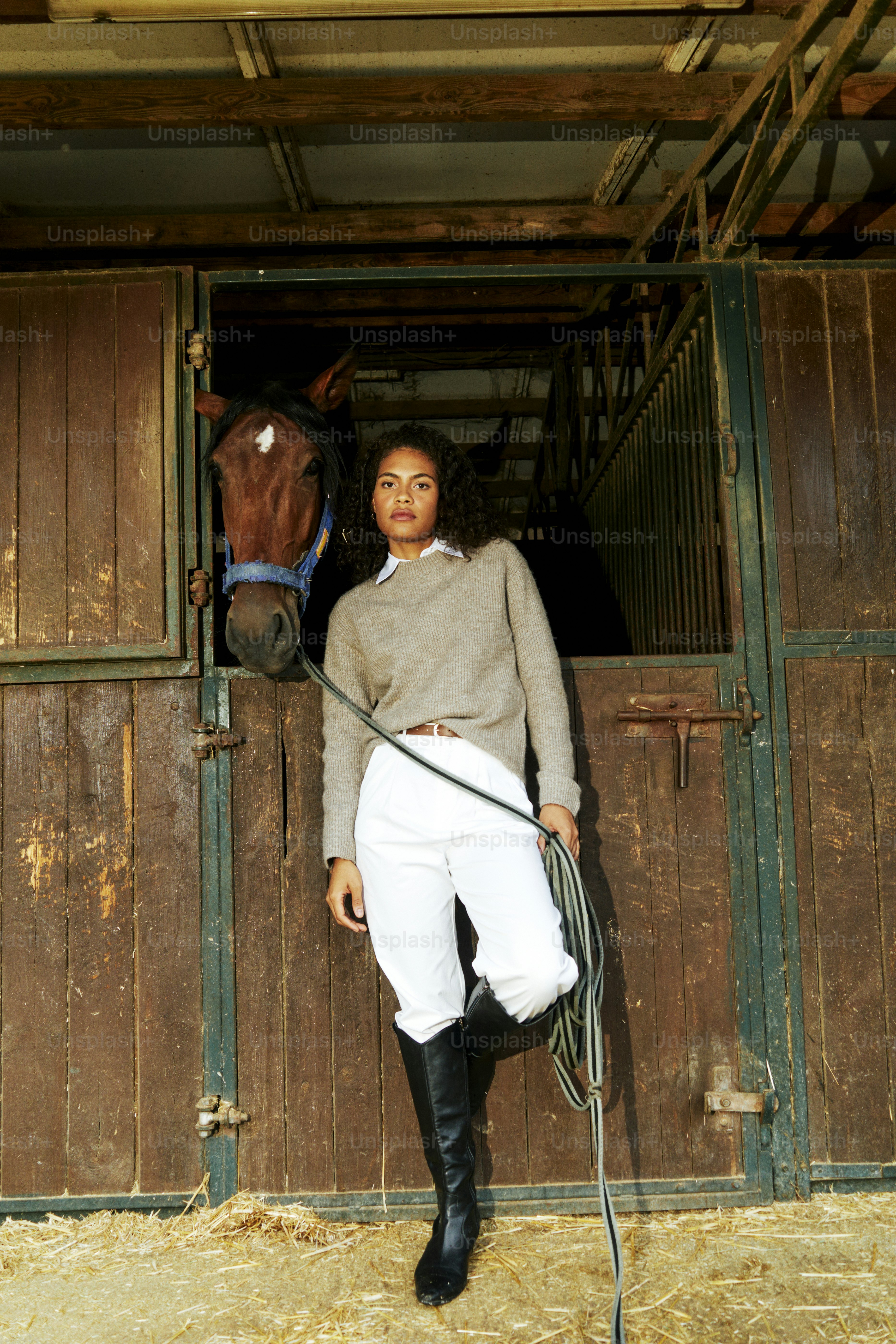 A woman standing next to a horse in a stable