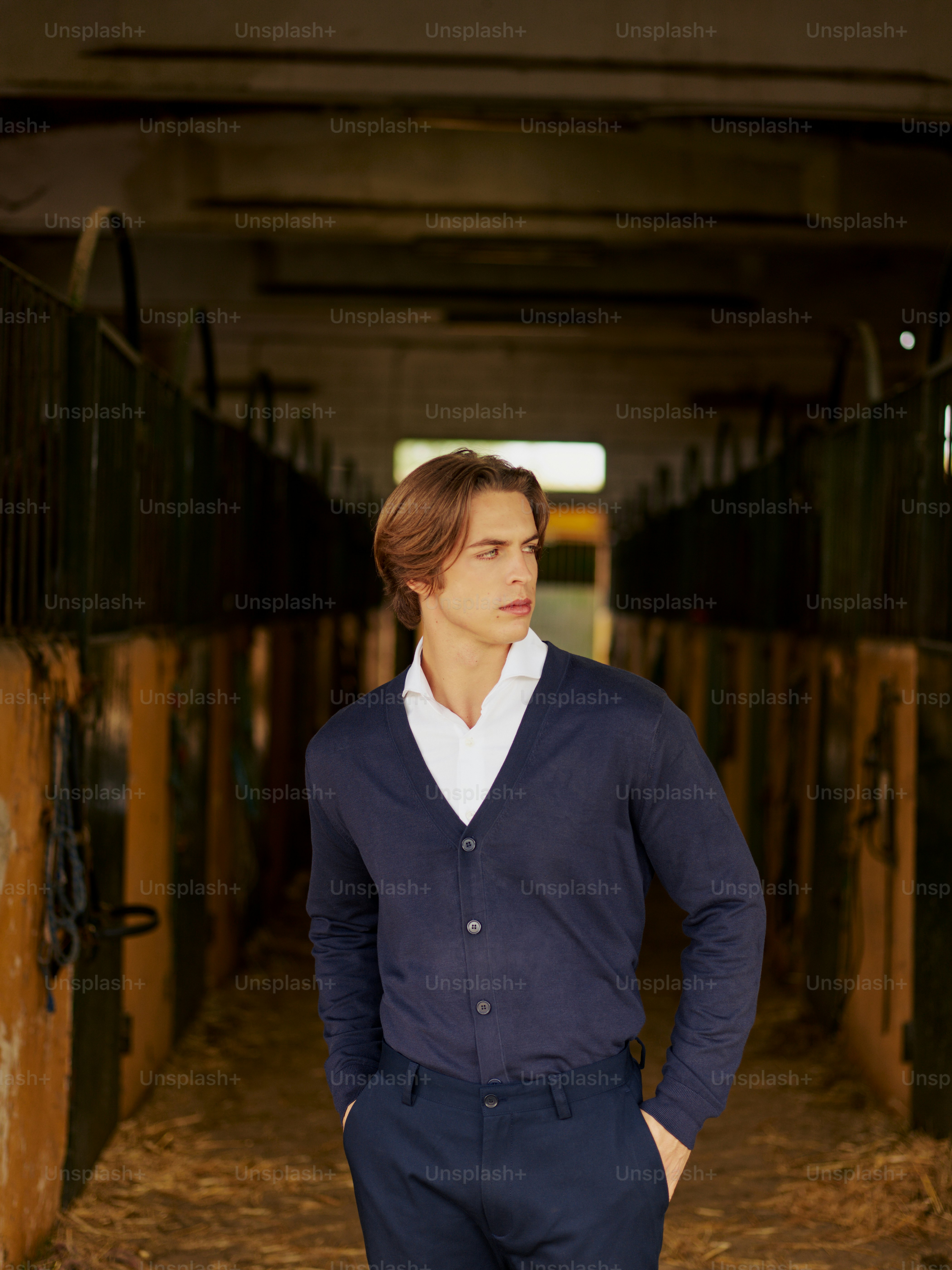 A man in a blue cardigan standing in a barn